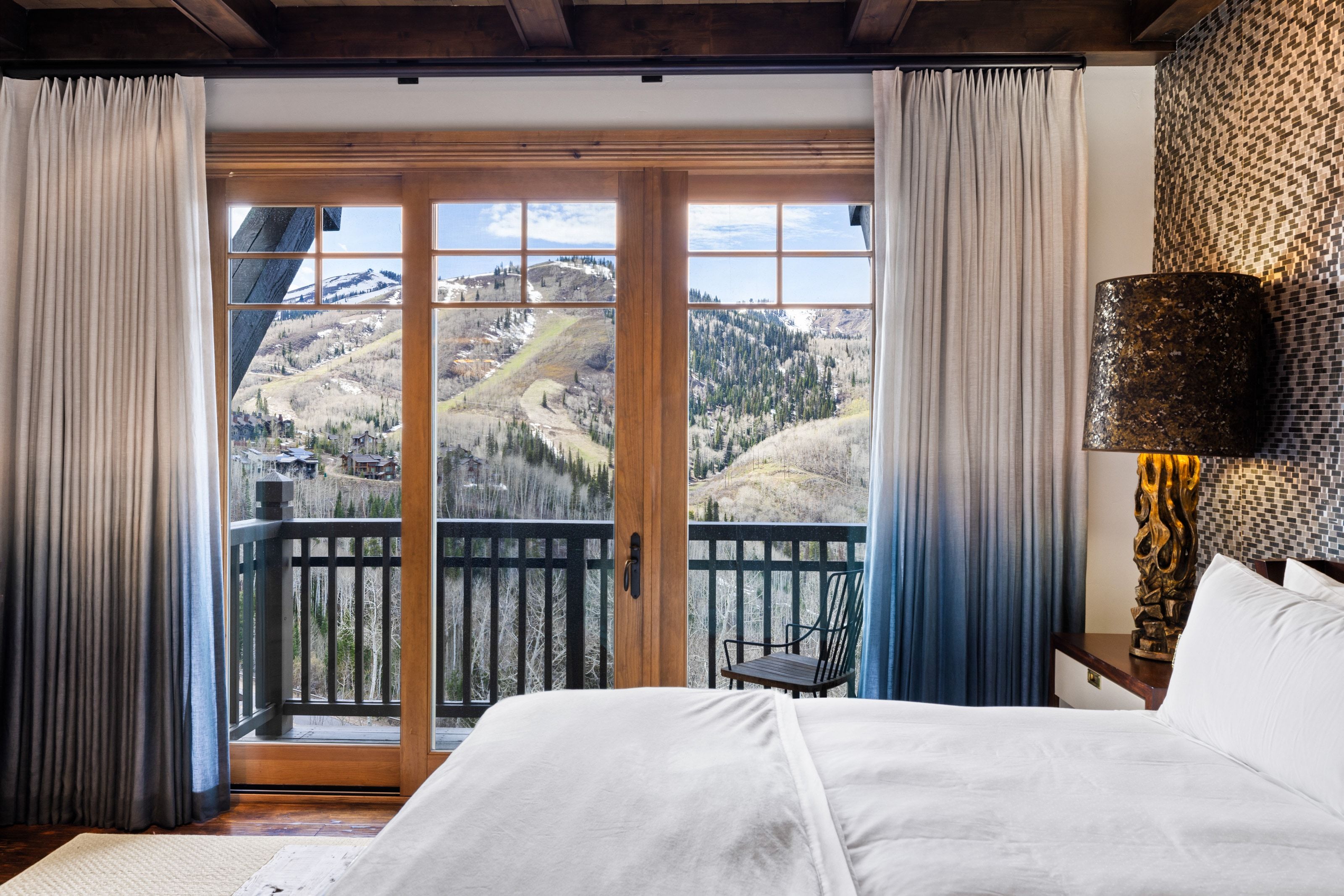 Expansive balcony with wood-frame glass doors, black metal railings, and mountain scenery