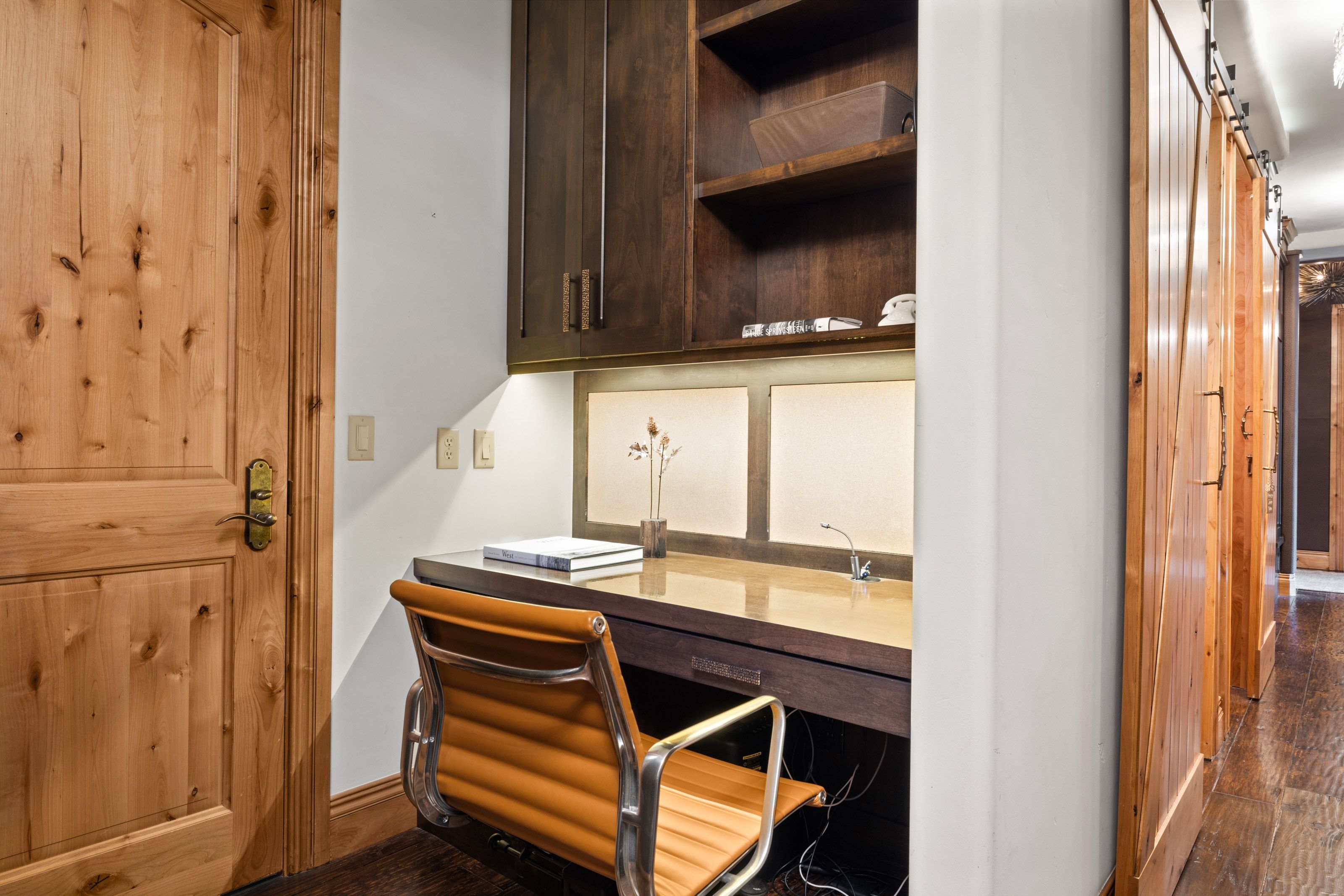 Dedicated workspace featuring a built-in wood-finish desk with task lighting and integrated shelving