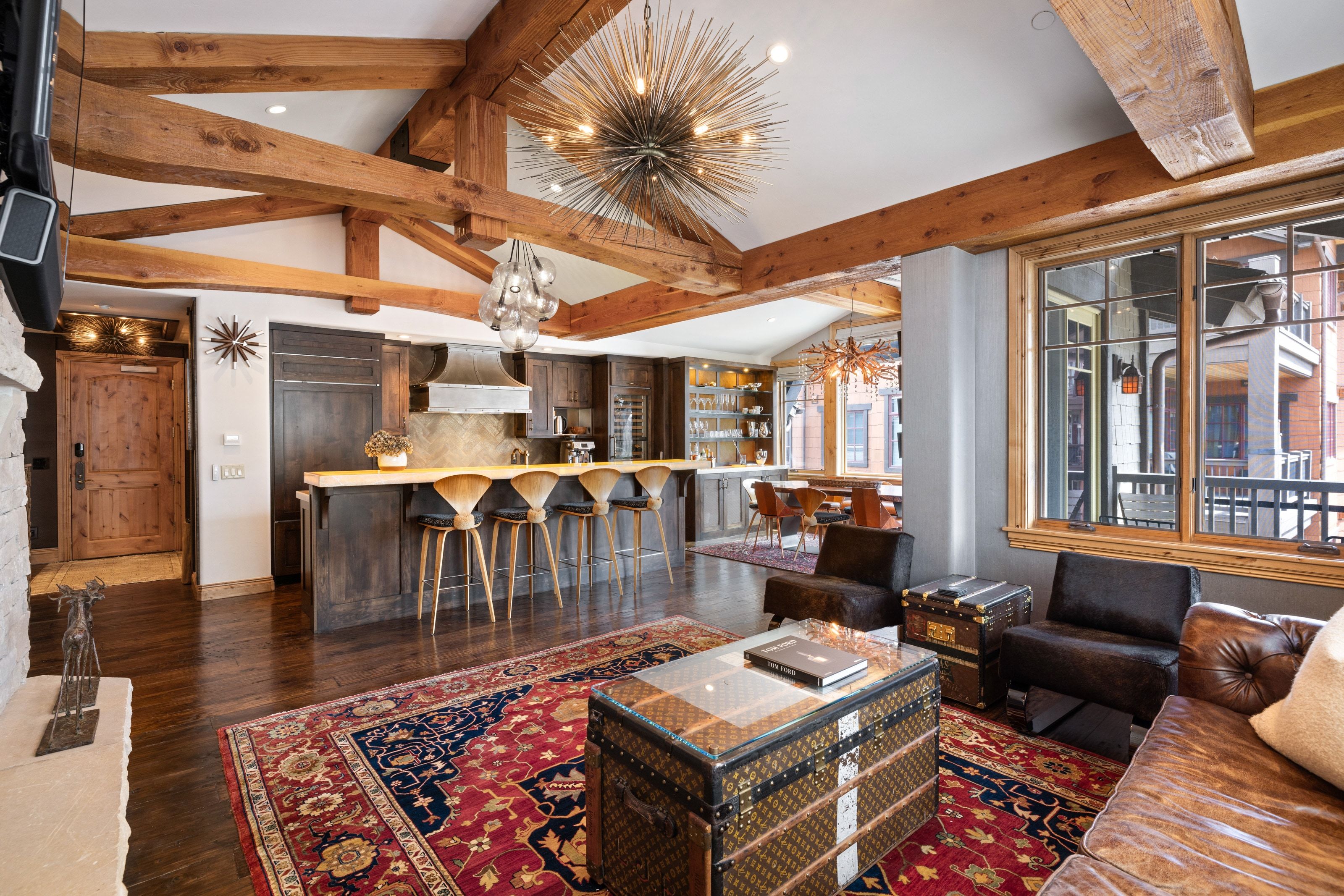 Great room featuring exposed wood beams, hardwood flooring, a stone fireplace, and a kitchen island with seating