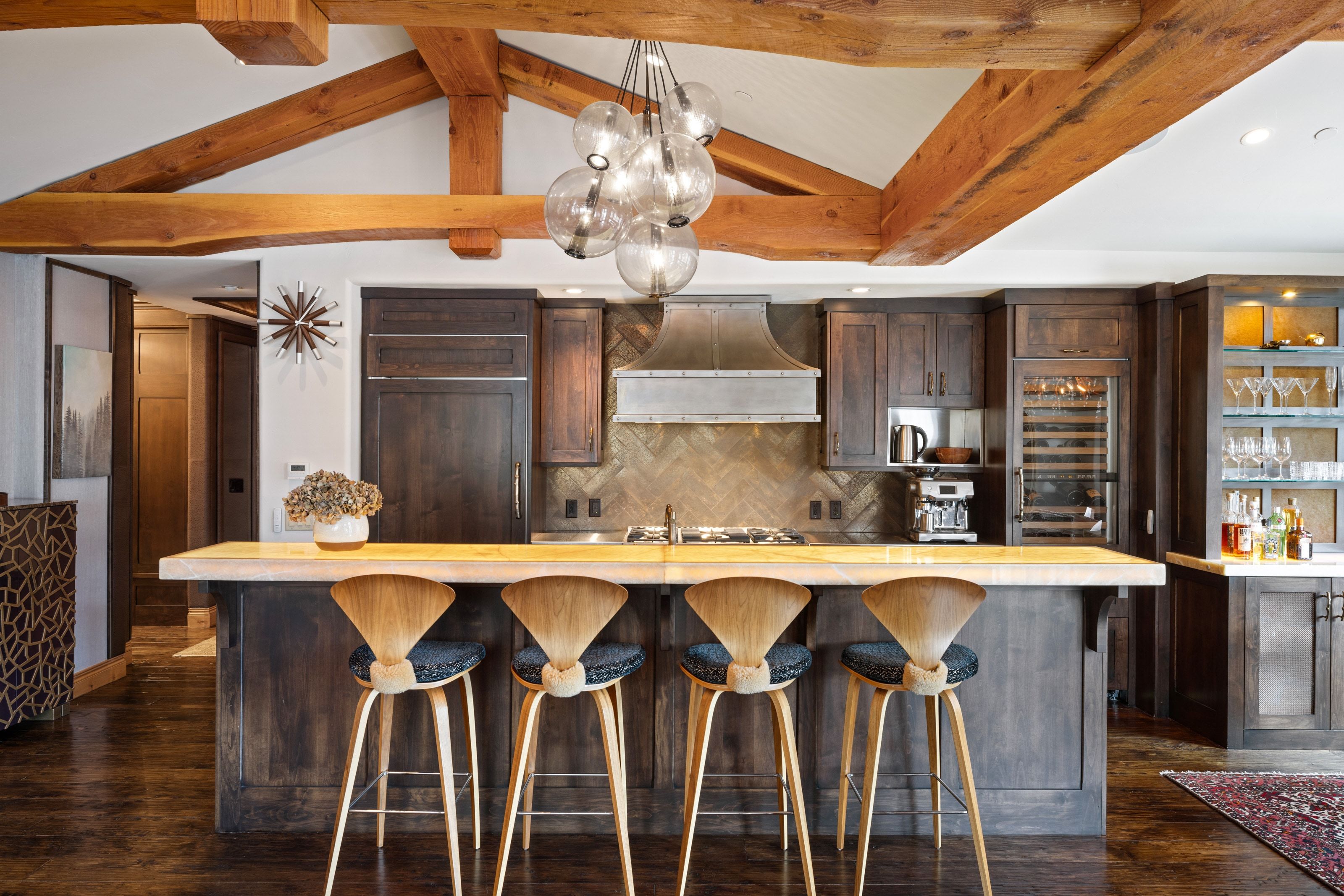 Kitchen featuring a large central island with a light wood countertop, exposed wood beams, dark wood cabinetry, a herringbone tile backsplash, and an integrated wine refrigerator