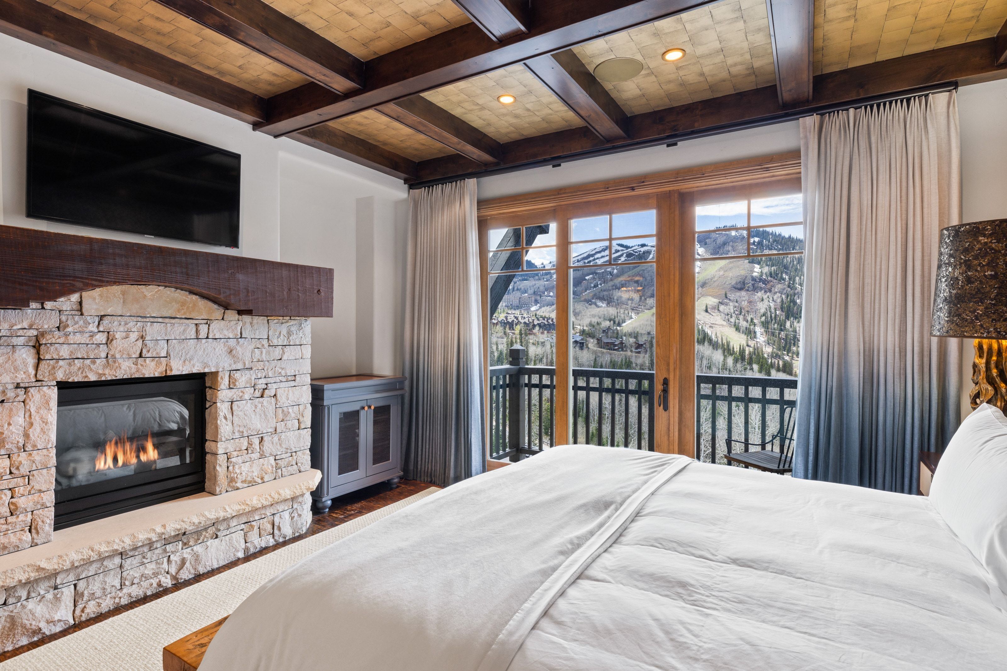 Room featuring a stone fireplace with a substantial timber mantel