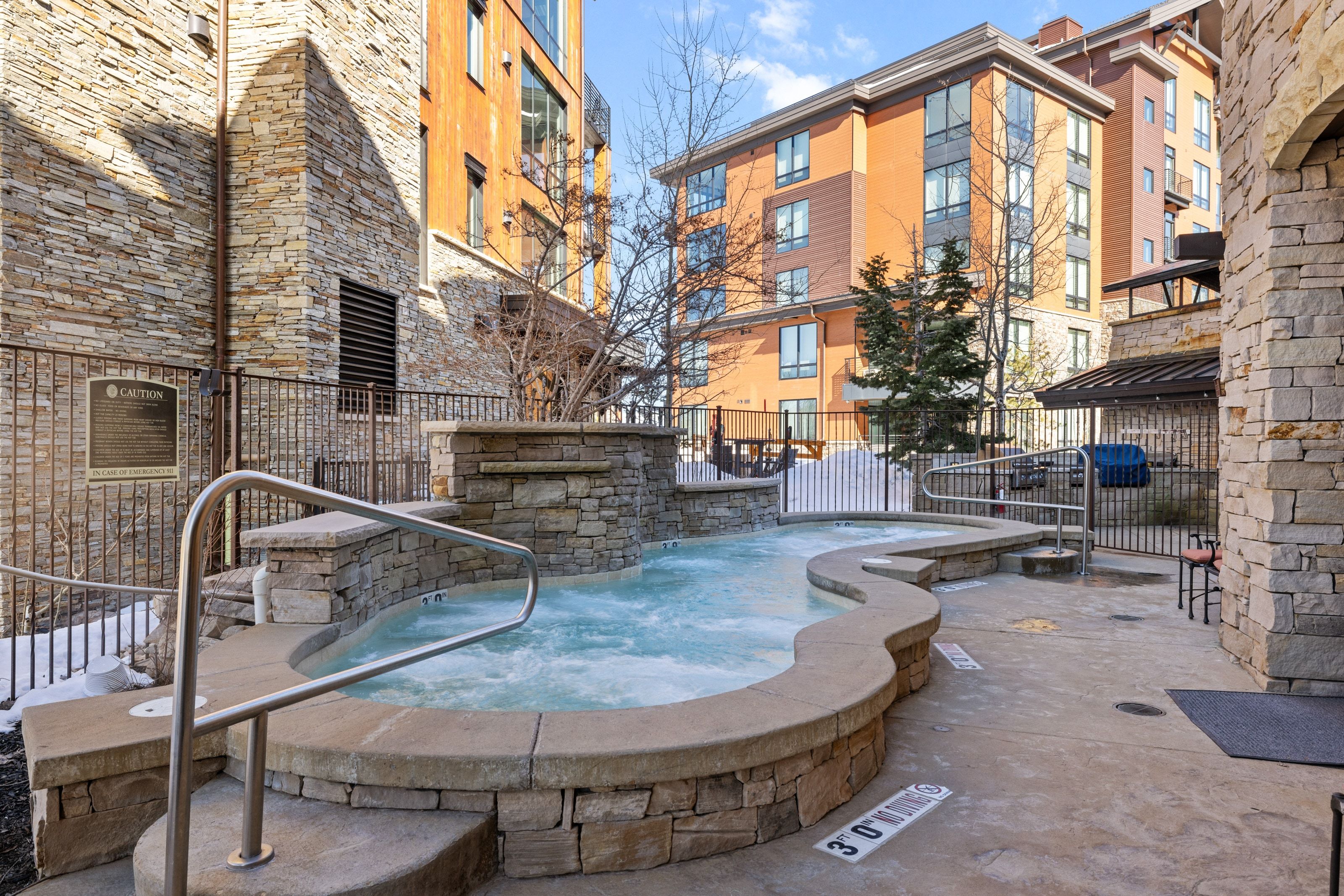 Outdoor spa featuring a stone surround, integrated water feature, and stainless steel handrails