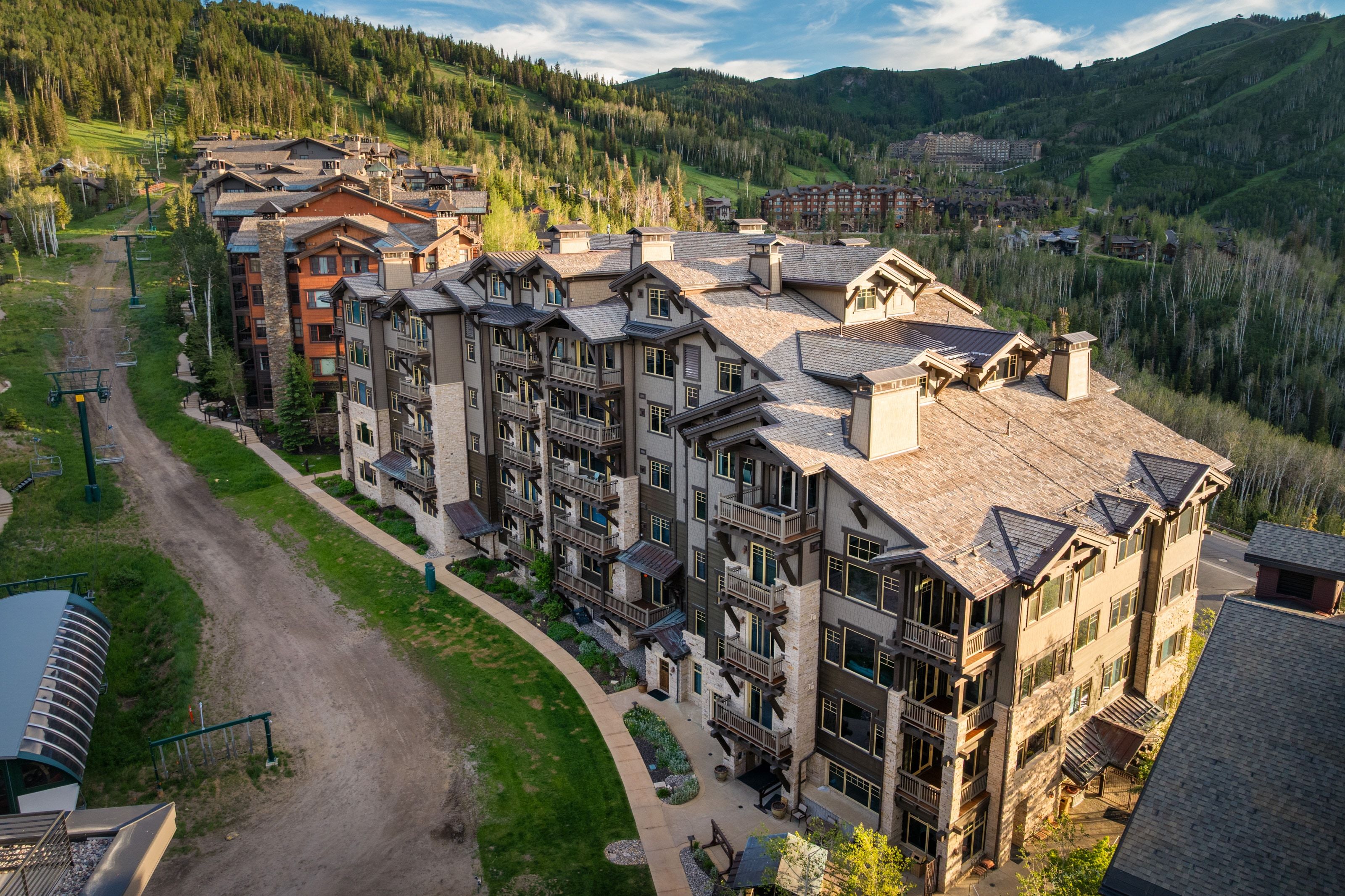 Multi-story condominium building featuring stone and wood-tone siding with multiple balconies
