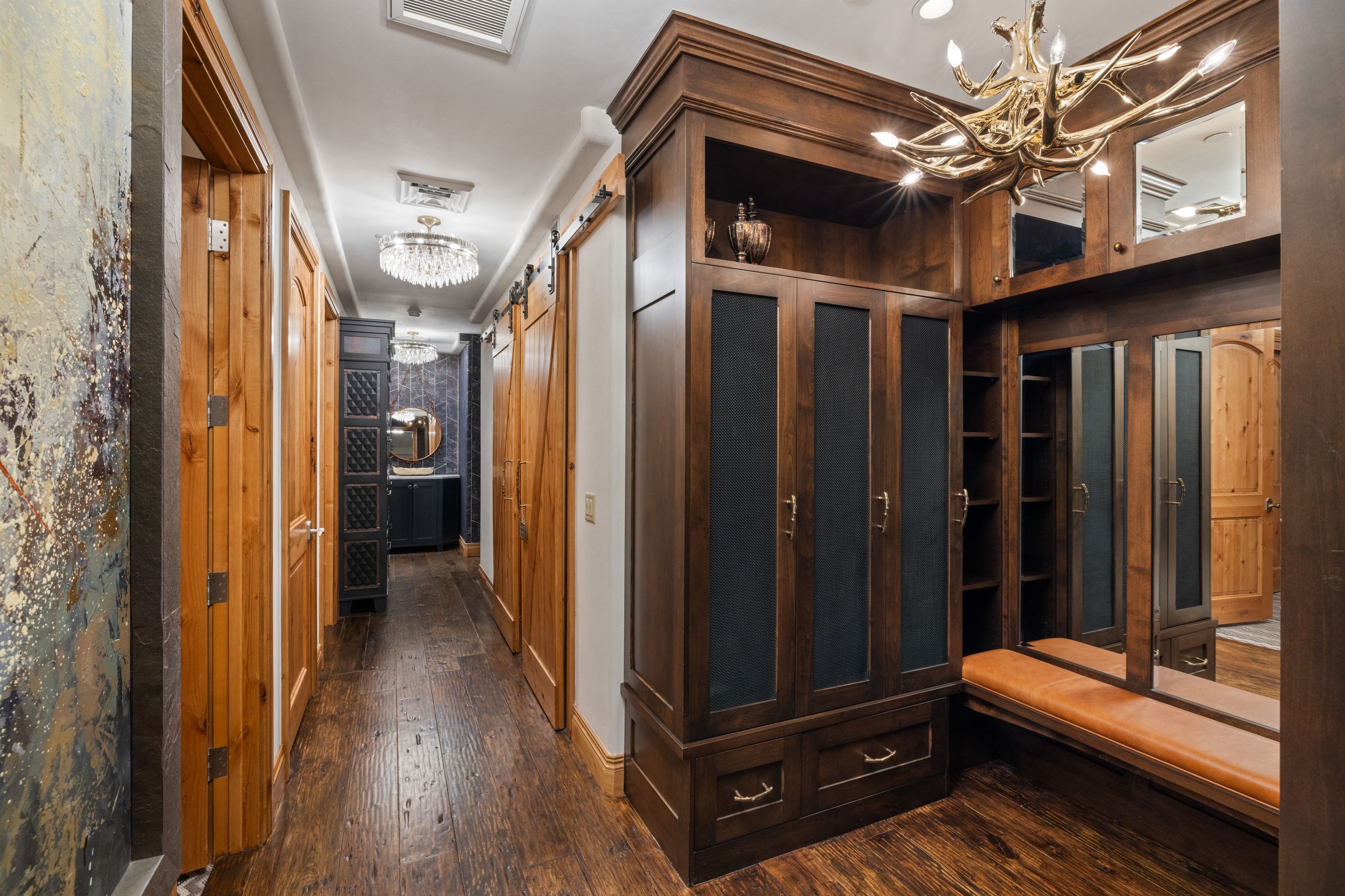 Custom-built wood cabinetry with integrated shelving and drawers, a mirrored wall, and a unique antler-style light fixture