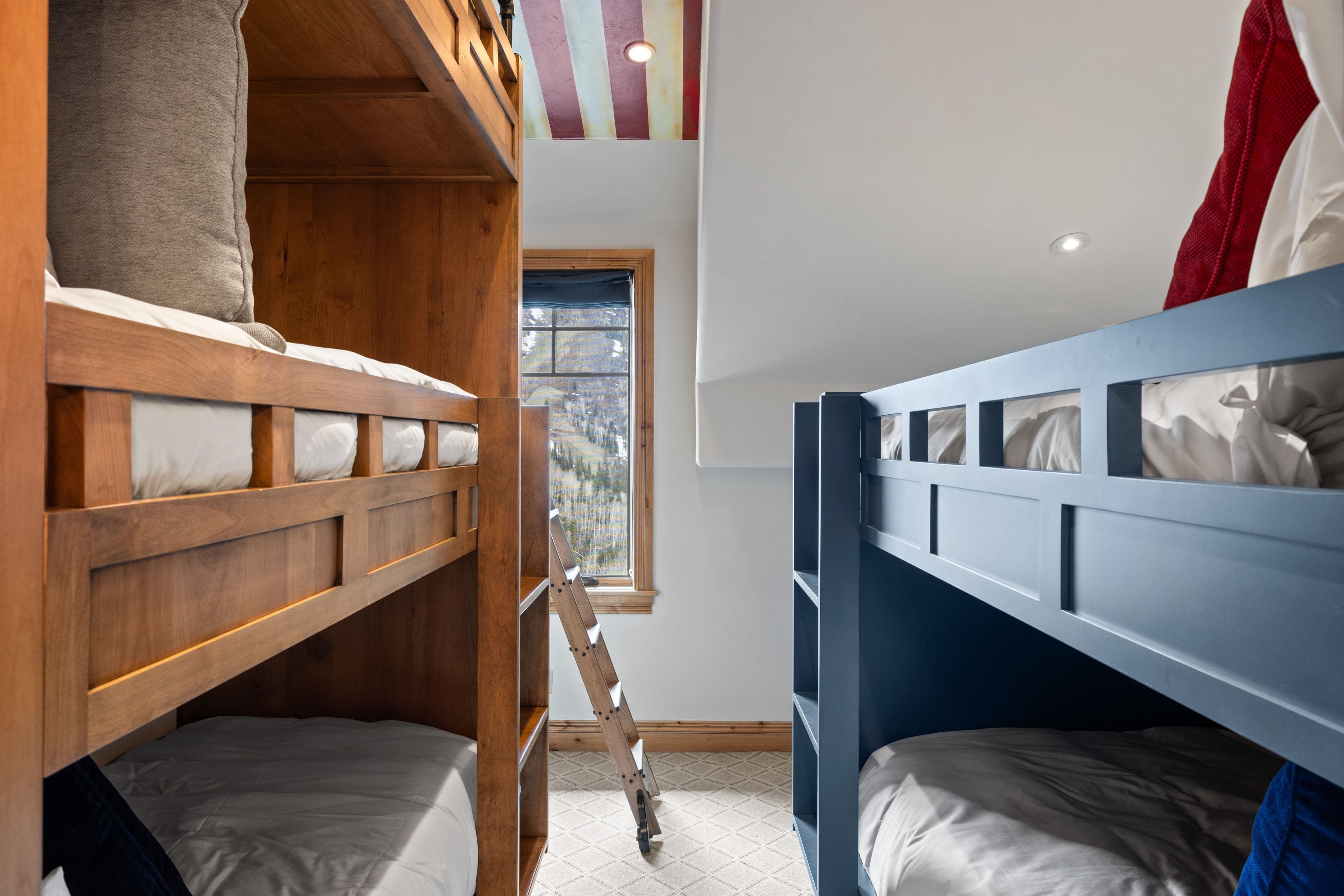 Bunk room featuring built-in wood-finish bunk beds and a painted blue bunk bed