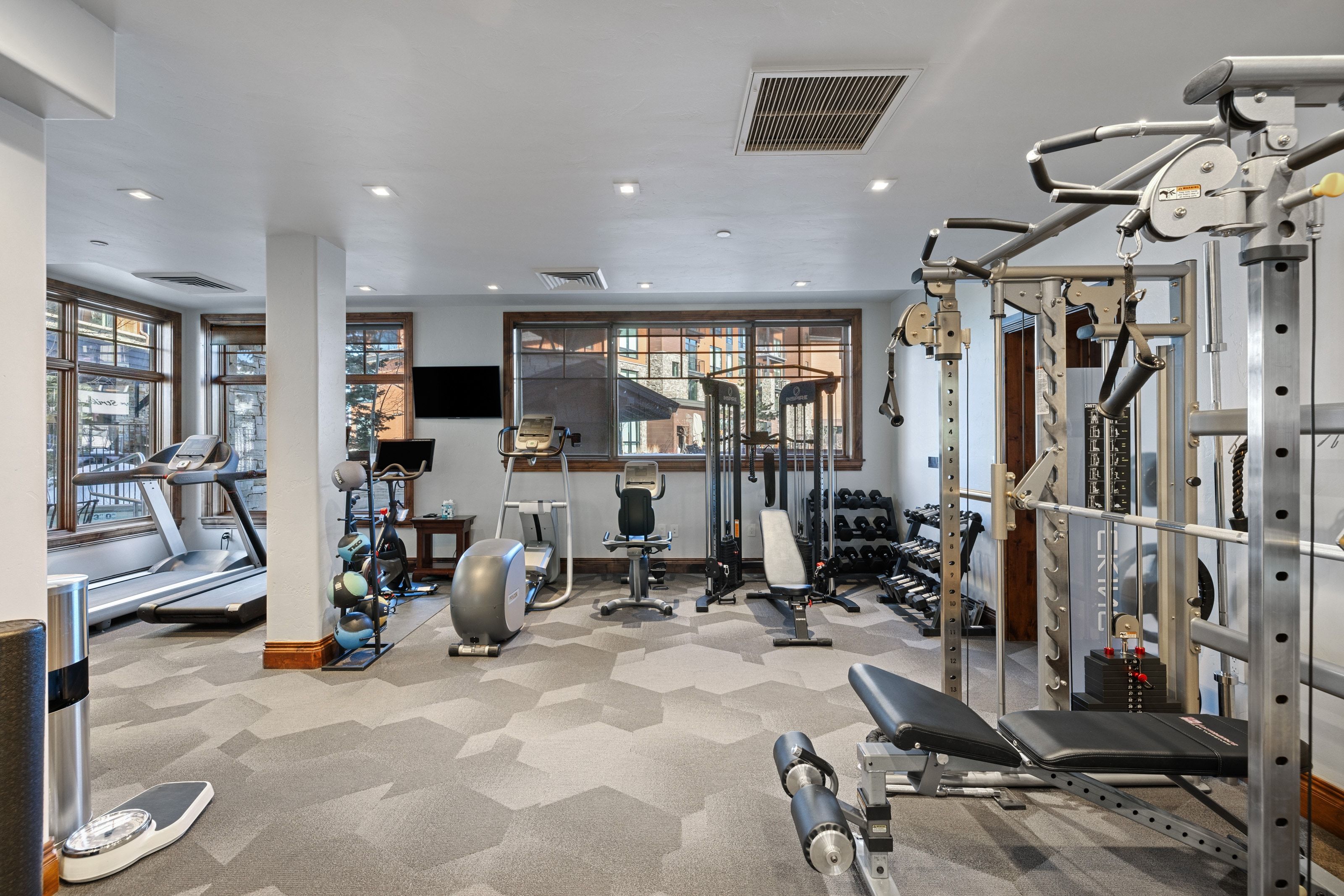 Dedicated fitness room featuring patterned carpet flooring, recessed lighting, and expansive windows with wood trim
