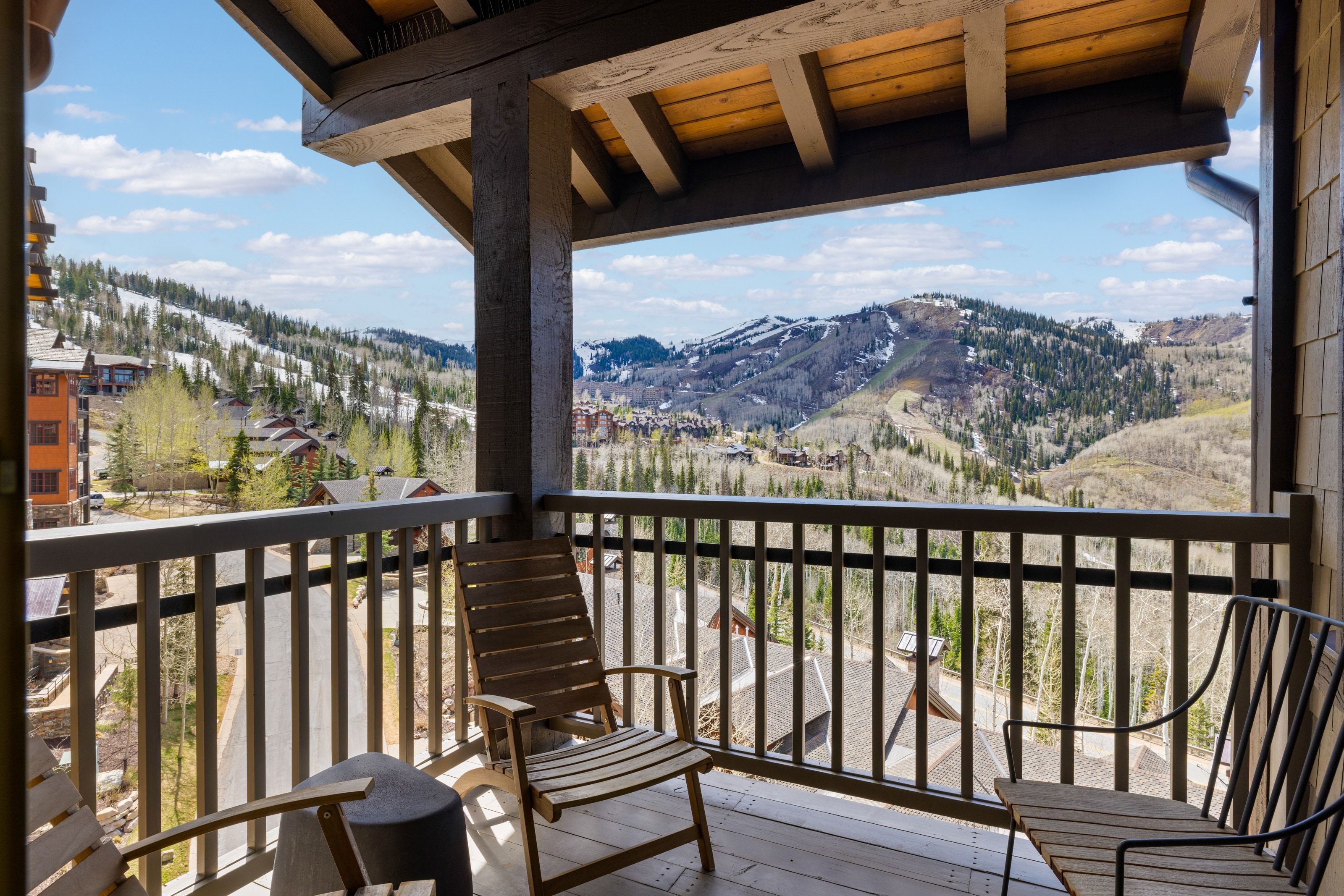 Private balcony featuring a wood-plank floor and sturdy wood railing, complemented by exposed wood beams and a wood-paneled ceiling