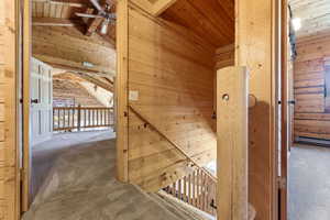 Expansive wood-paneled interior featuring a carpeted landing, staircase with wood railings, and a vaulted ceiling with a built-in ceiling fan