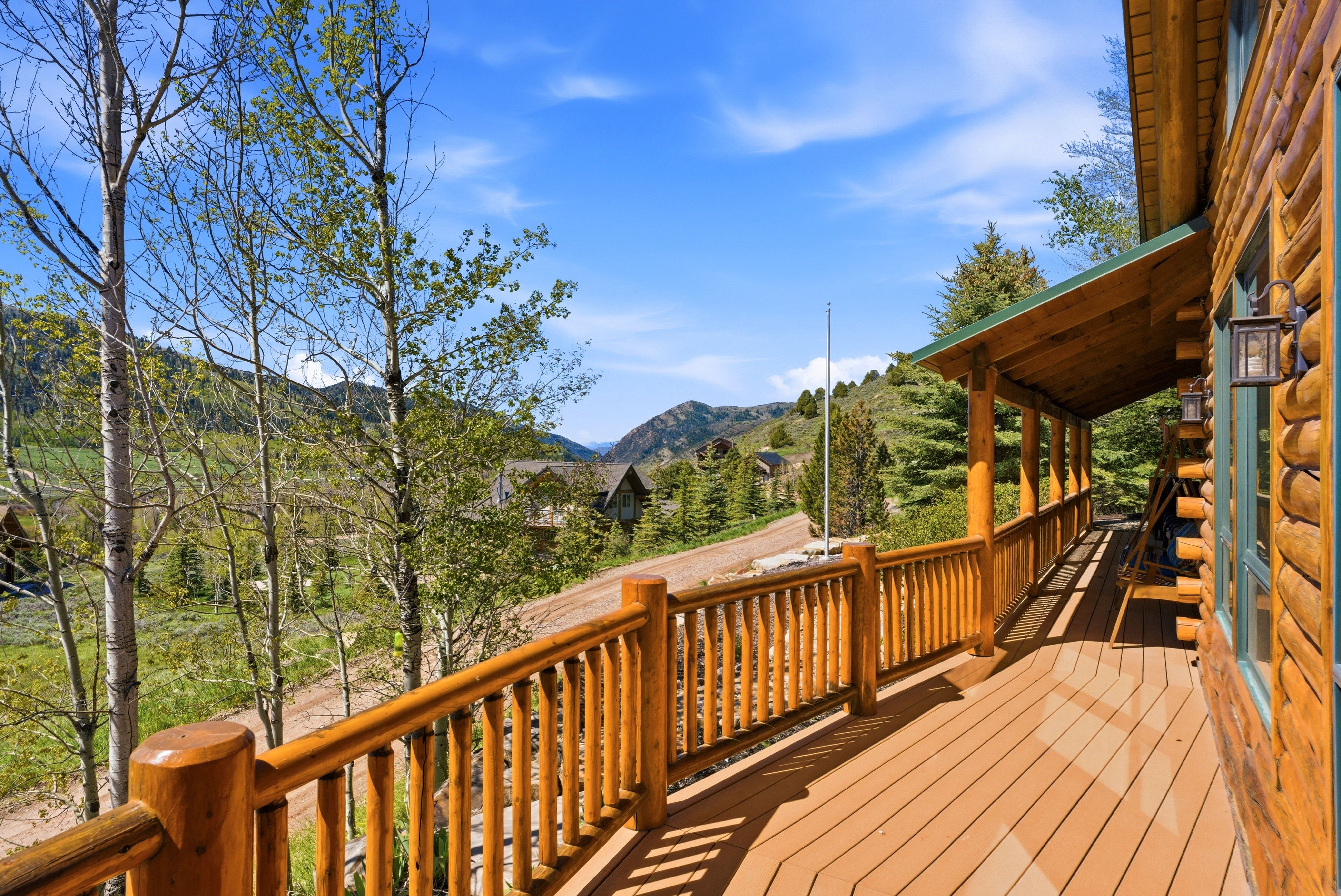 Expansive outdoor deck featuring log railing and wood-finish flooring
