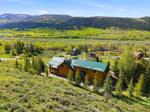 Log-style residence featuring a green metal roof, multiple chimneys, and a covered porch