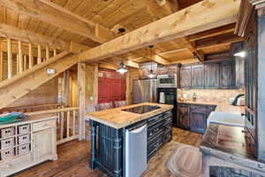 Kitchen featuring a central island with wood countertop and built-in cooktop, dark wood cabinetry, and stainless steel appliances