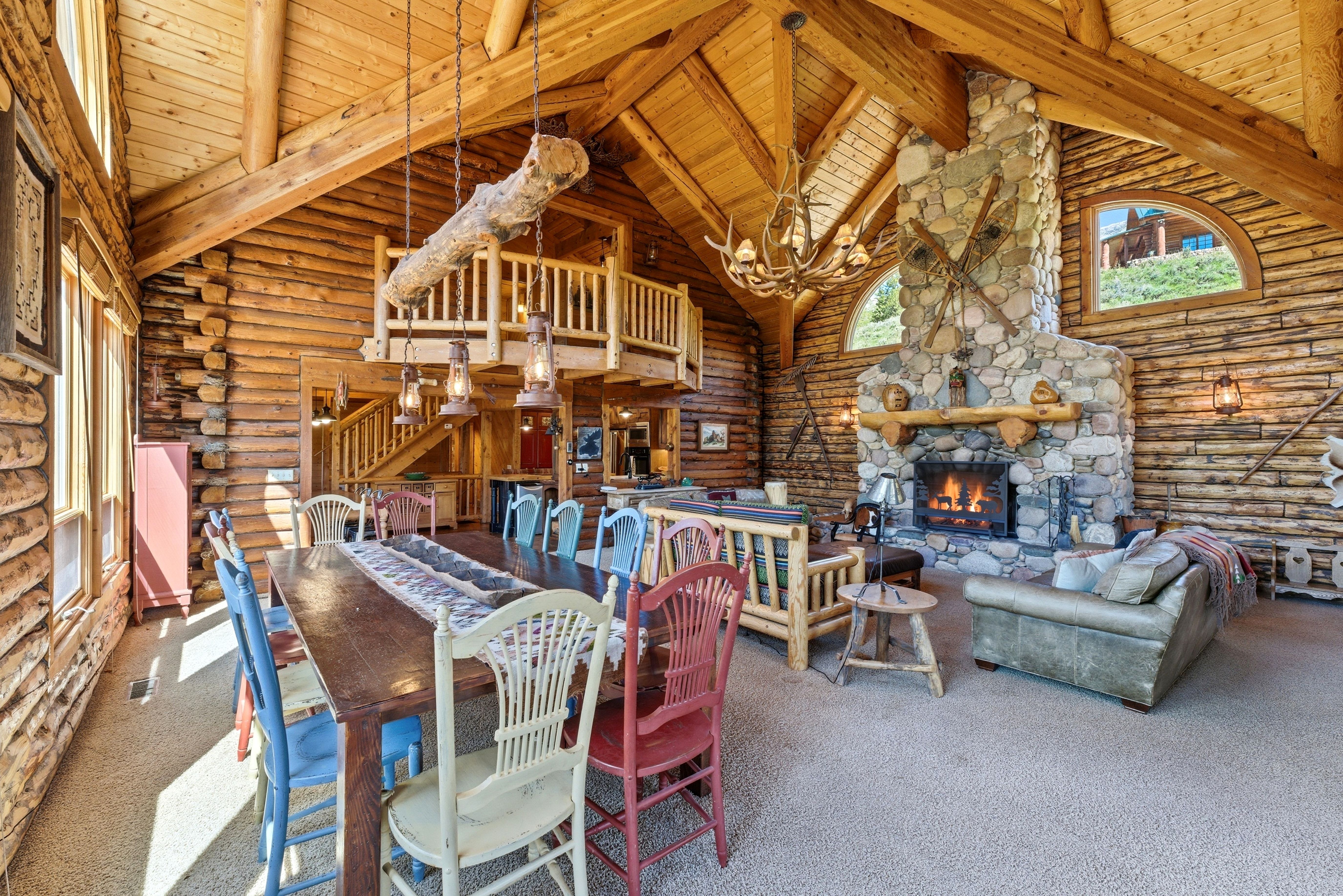 Spacious great room featuring exposed log walls, a vaulted wood-plank ceiling with exposed beams, and a substantial stone fireplace