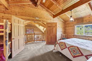 Wood-paneled room featuring vaulted ceilings with exposed beams and a window overlooking a natural landscape