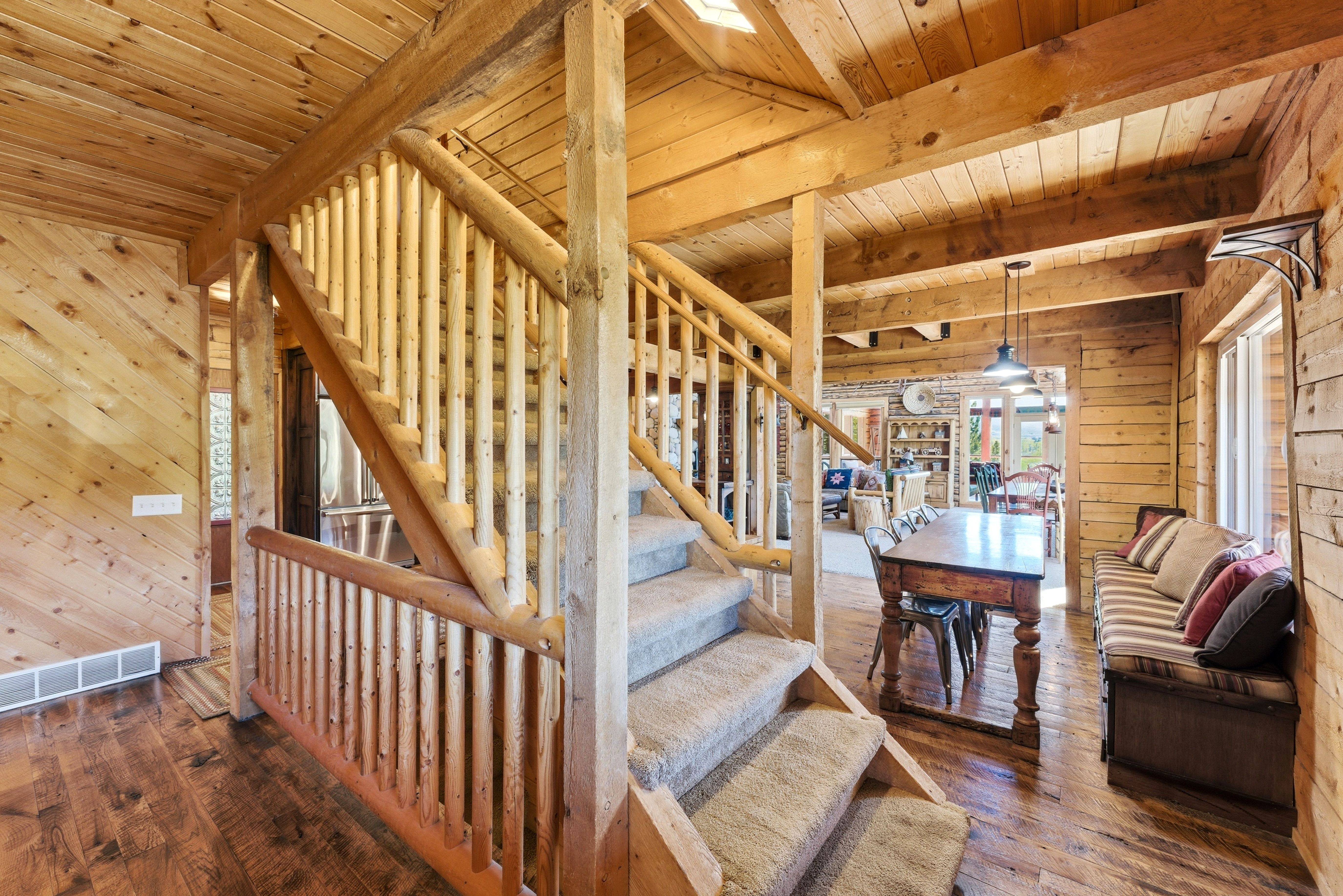 Rustic wood staircase with carpeted treads, log railings, and wood-paneled walls