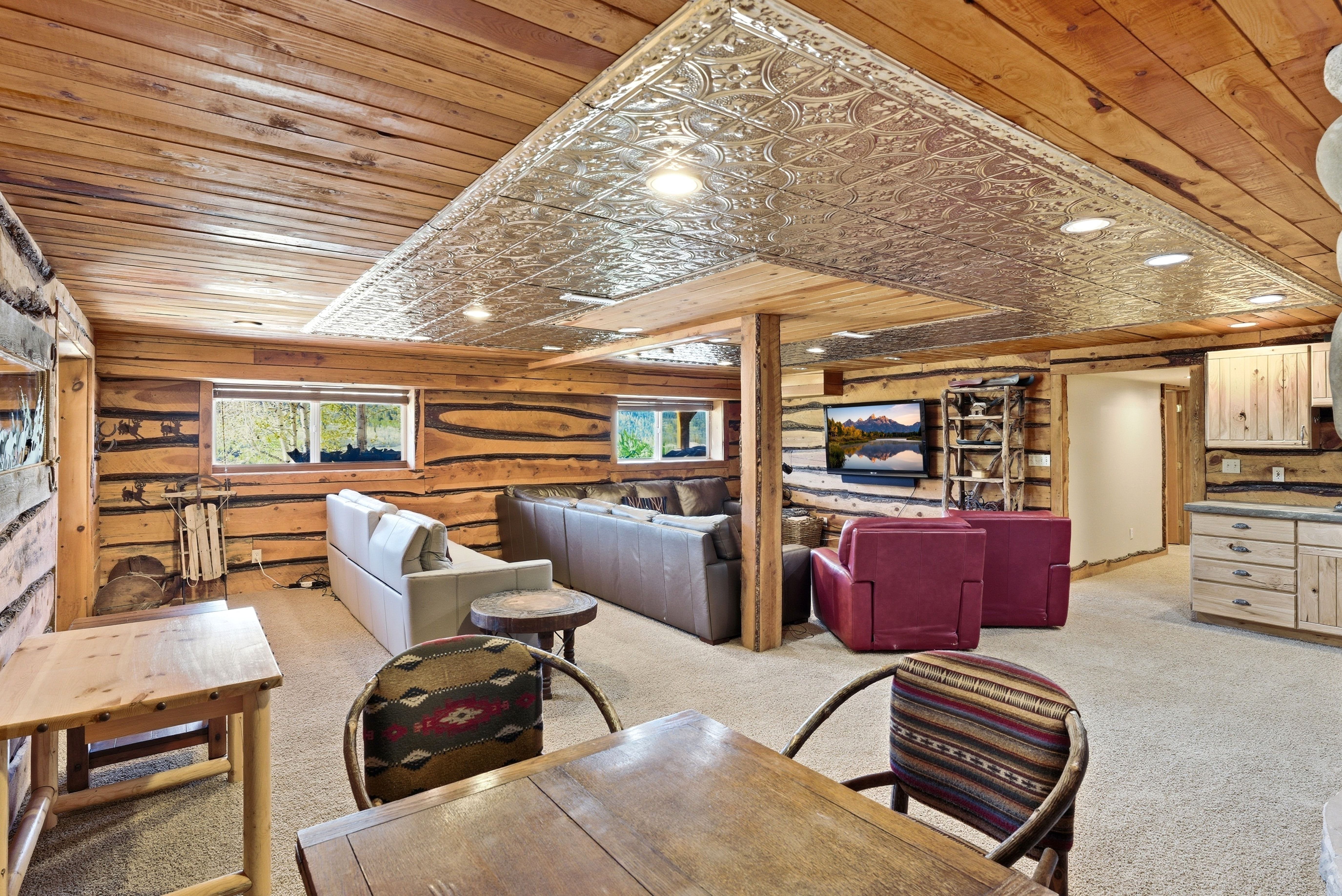 Spacious entertainment area featuring knotty pine log walls, a pressed tin ceiling detail, and recessed lighting