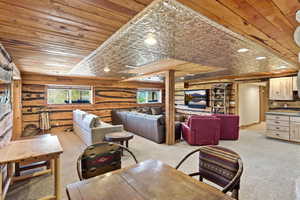 Spacious entertainment area featuring knotty pine log walls, a pressed tin ceiling detail, and recessed lighting