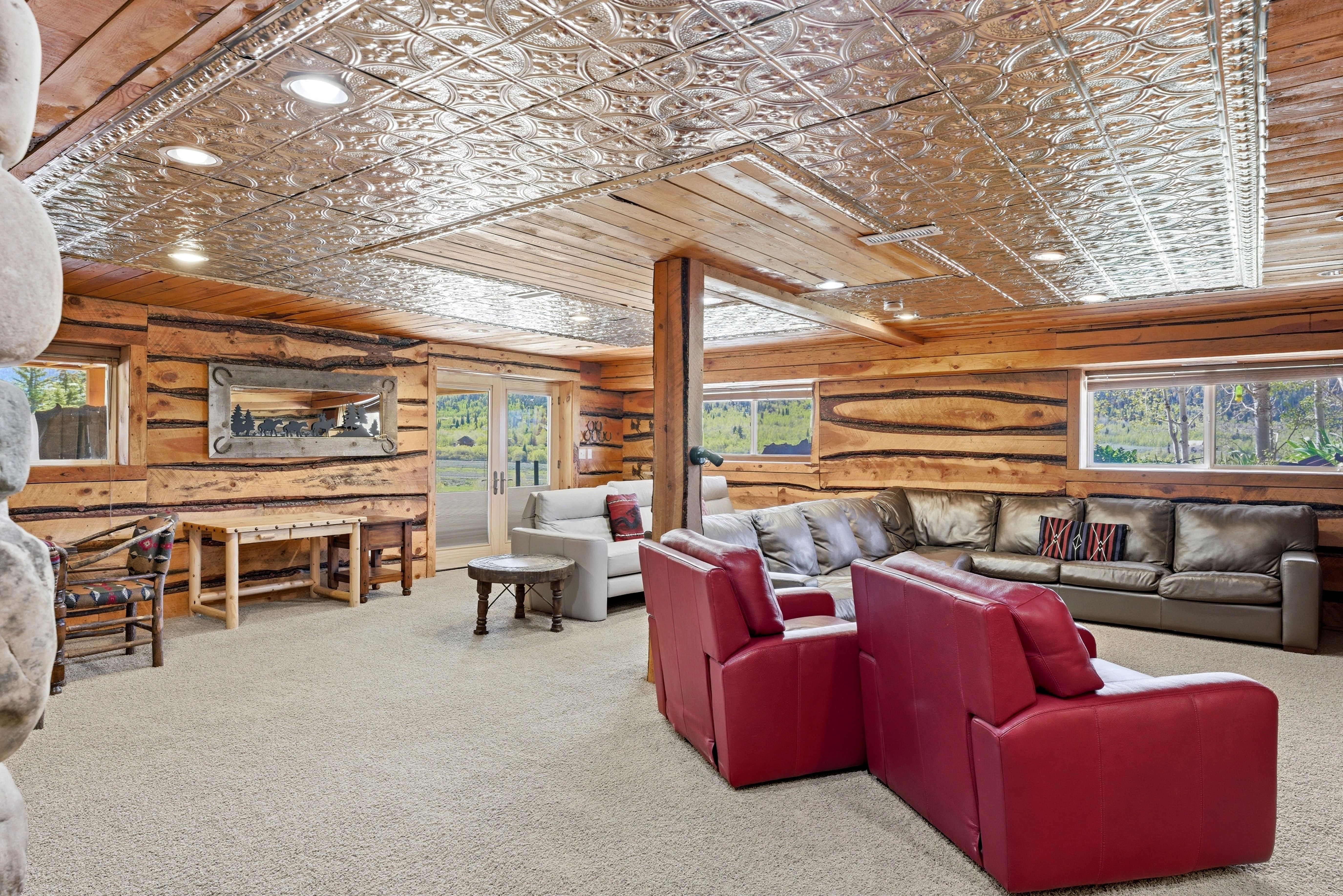 Expansive living area featuring a decorative pressed tin ceiling, wood-plank walls, recessed lighting, and large windows