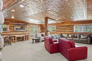 Expansive living area featuring a decorative pressed tin ceiling, wood-plank walls, recessed lighting, and large windows