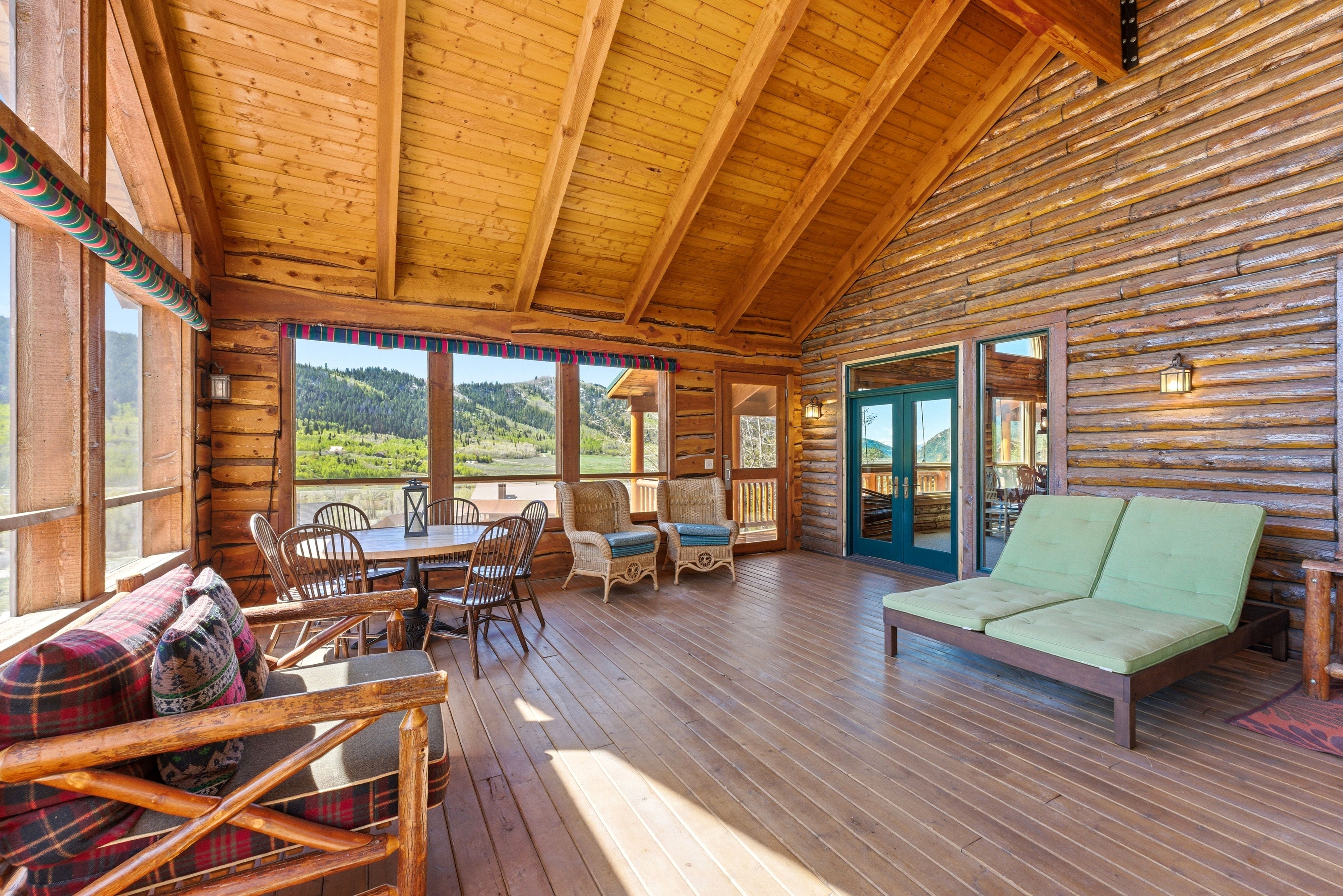 Expansive covered porch featuring wood-finish flooring, log wall construction, and a vaulted wood-plank ceiling