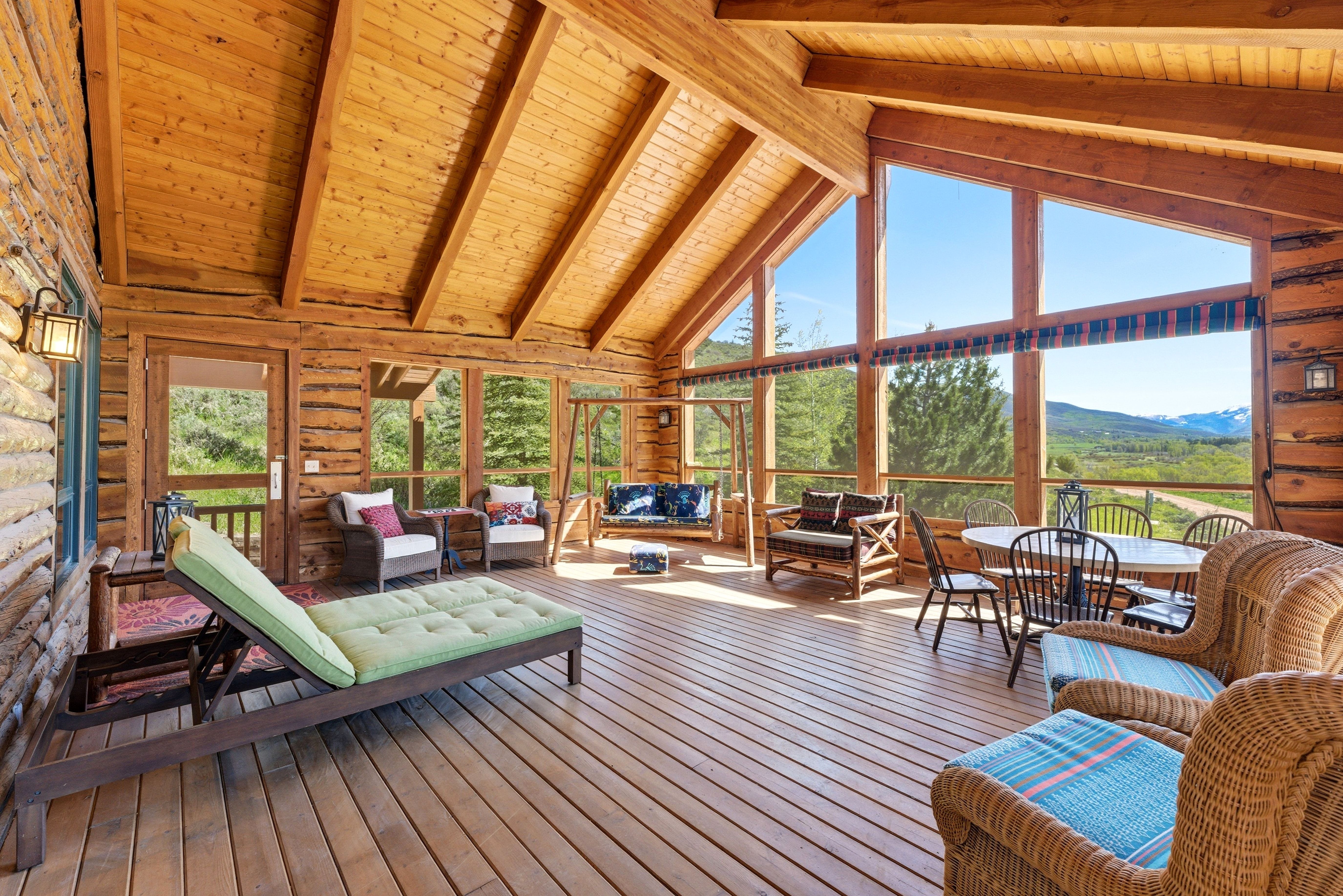 Expansive covered deck featuring a wood-plank floor, exposed timber beams, and a vaulted wood-plank ceiling