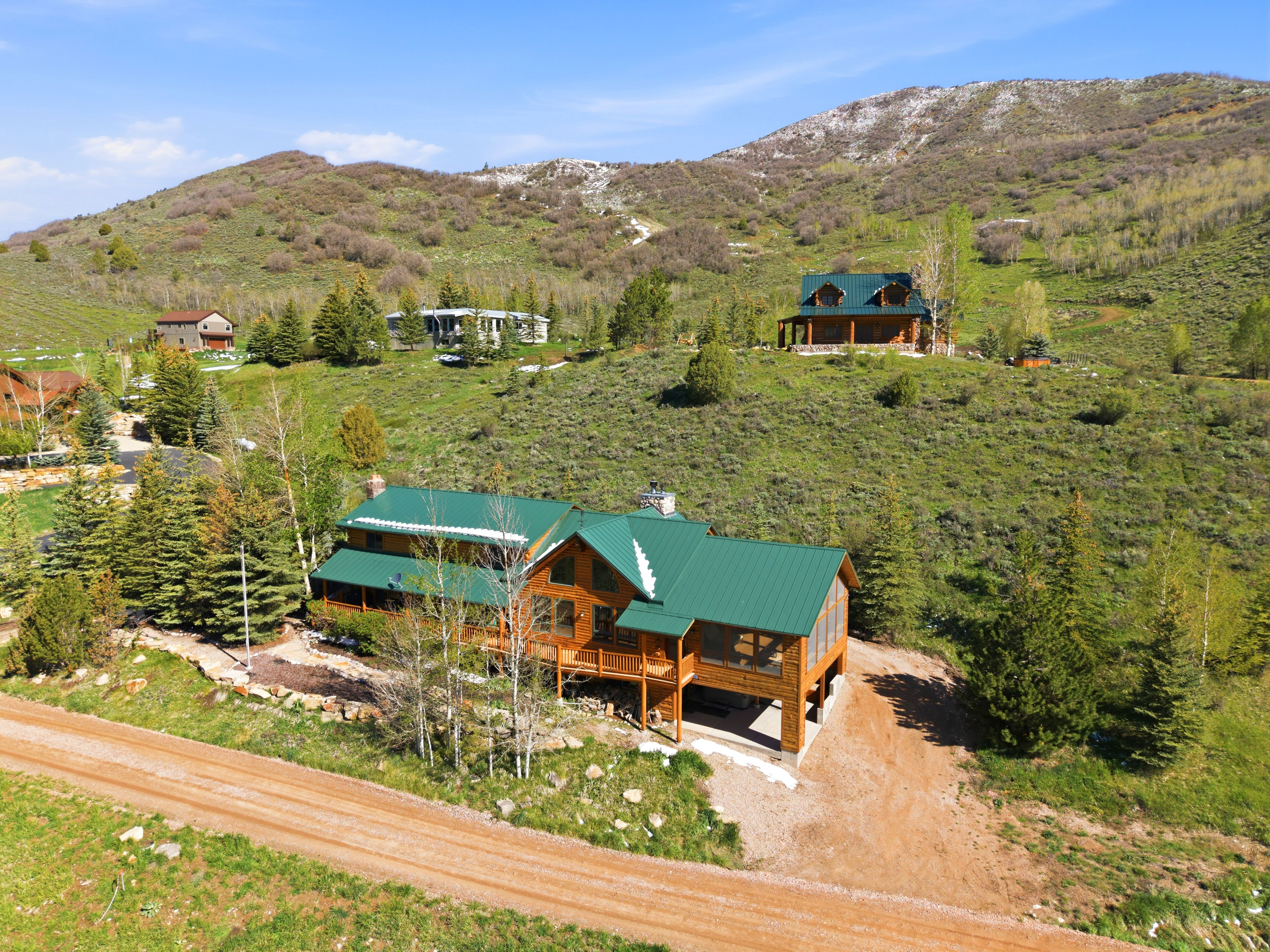 Log-style residence with a green metal roof and multiple exterior decks