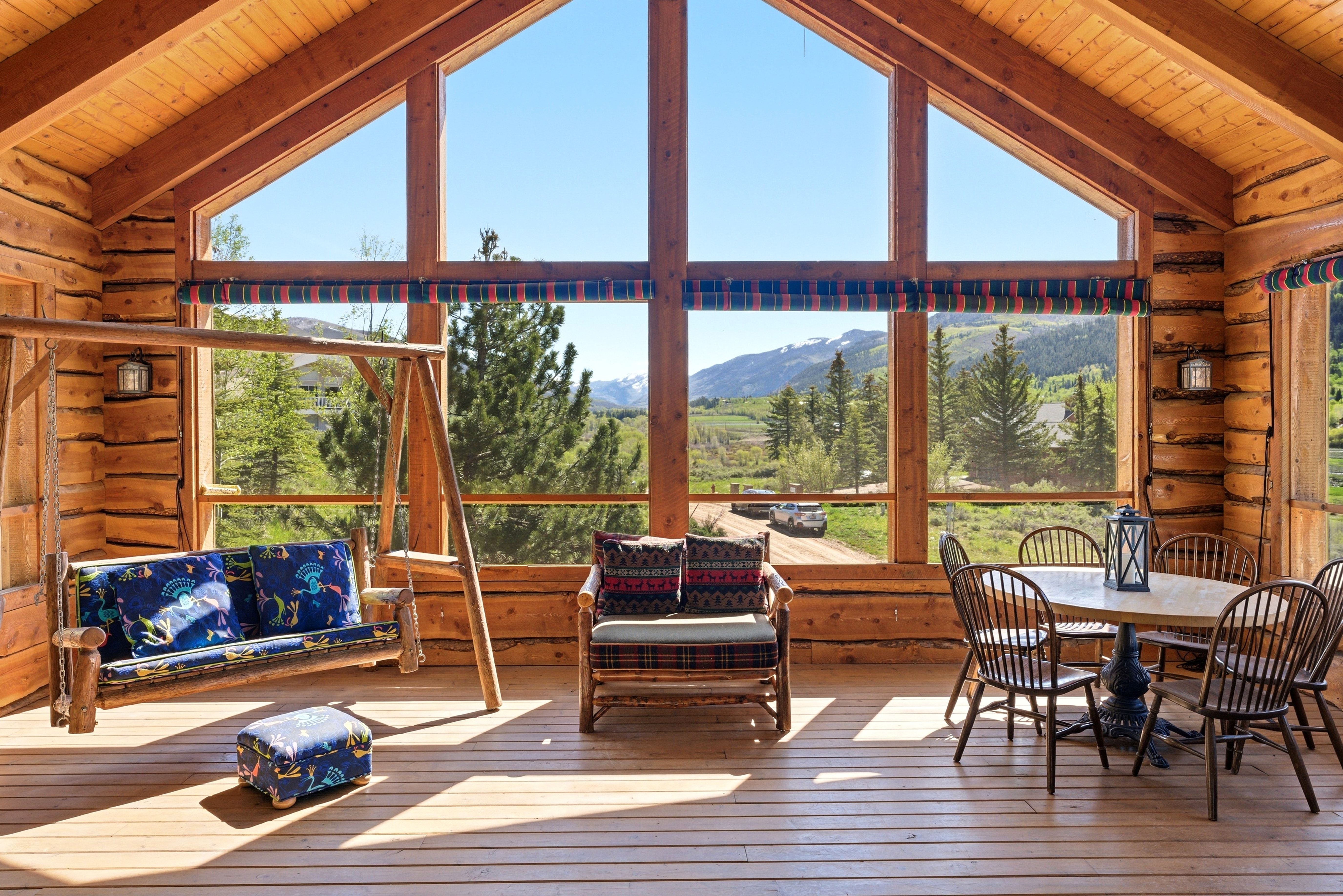 Sunroom featuring extensive log construction, a wood plank ceiling, and large picture windows