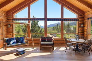 Sunroom featuring extensive log construction, a wood plank ceiling, and large picture windows