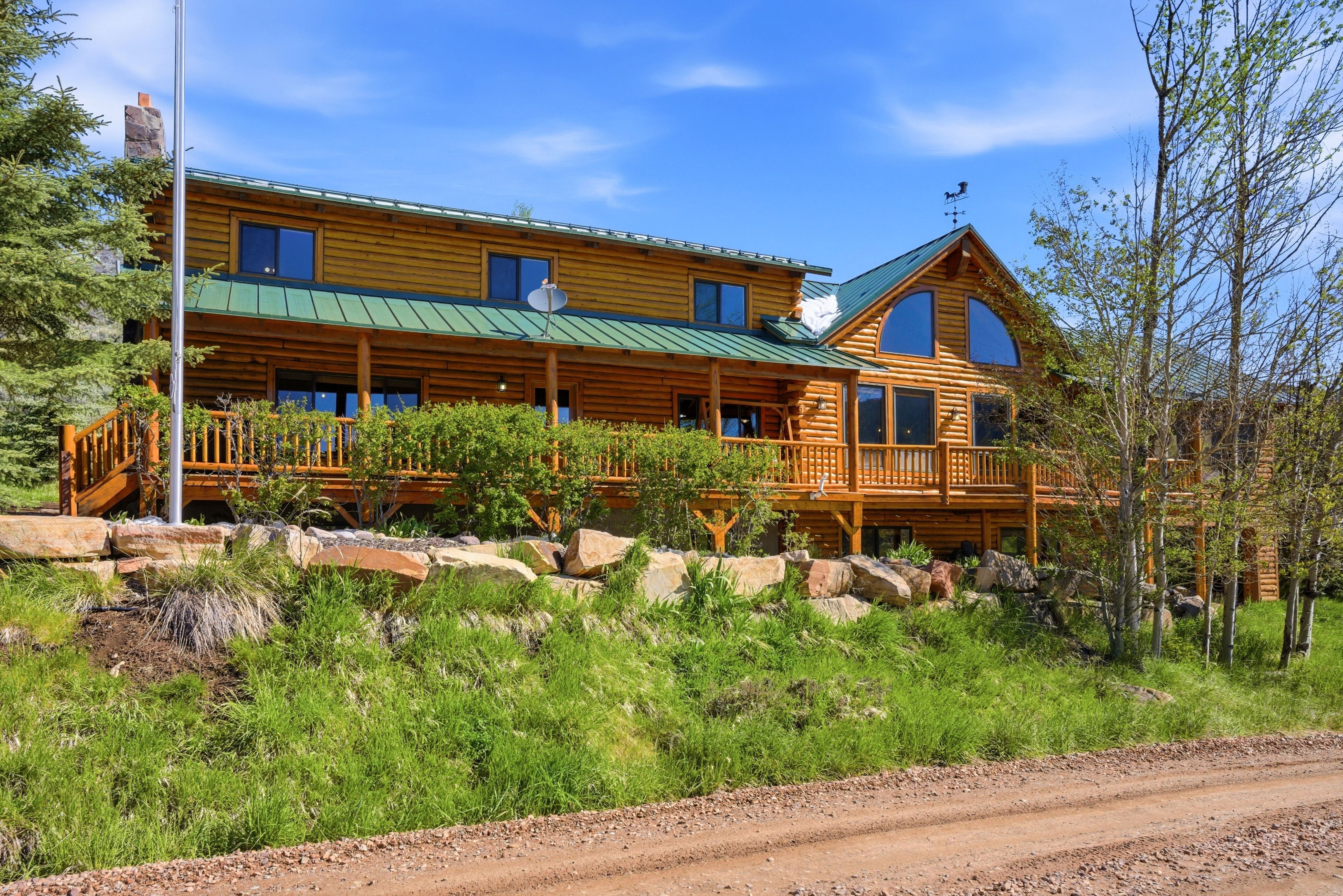 Log home featuring a green metal roof and expansive wooden decking