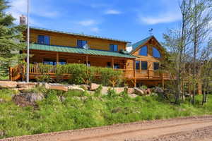 Log home featuring a green metal roof and expansive wooden decking