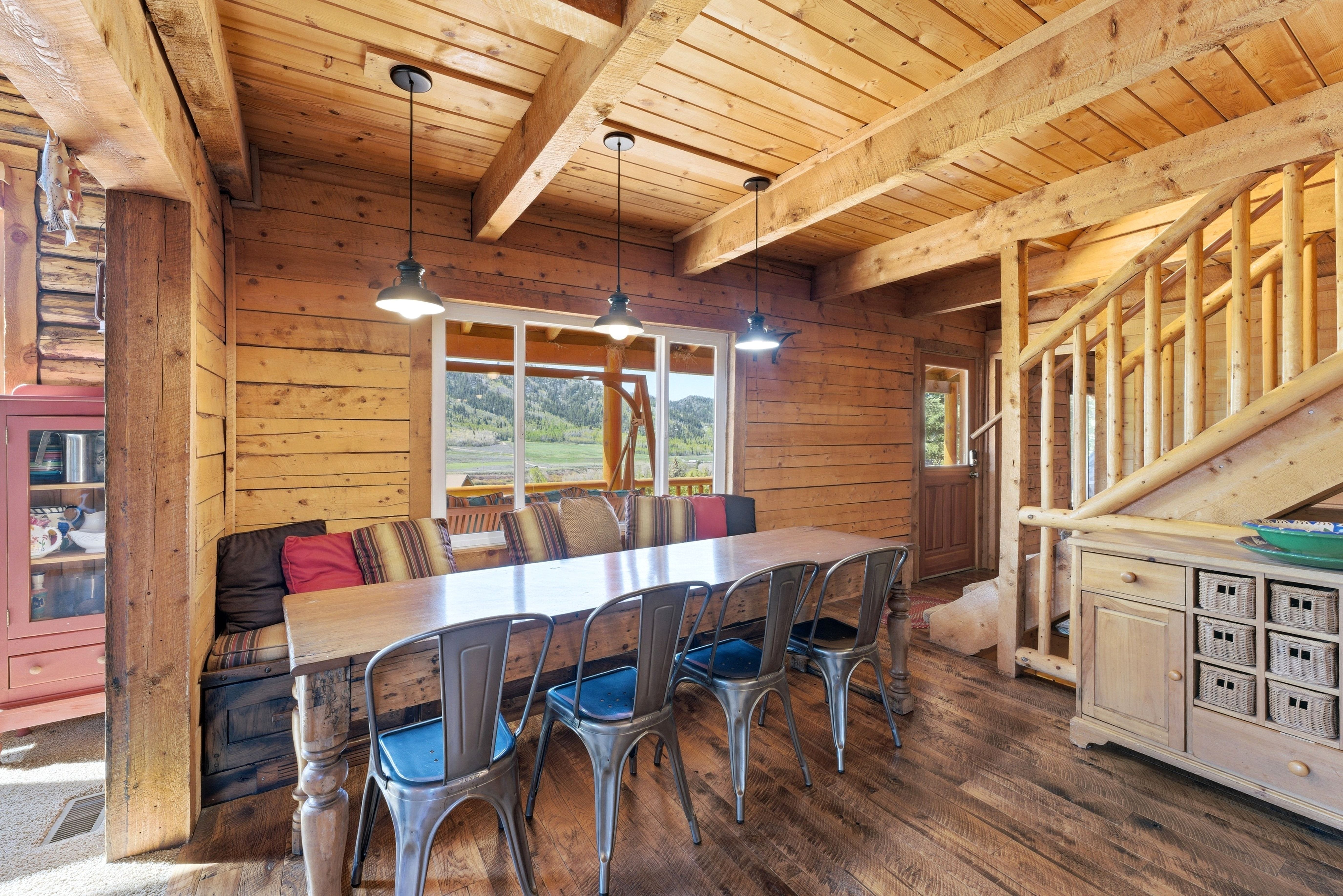Spacious dining area featuring wood-finish flooring, exposed wooden beams, and pendant lighting