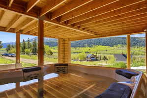 Covered outdoor spa with multiple seating positions, positioned under a wood-beamed ceiling