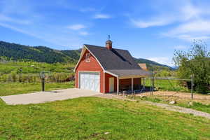Red barn-style structure featuring a cupola, attached covered porch, white garage door, and decorative gable vent