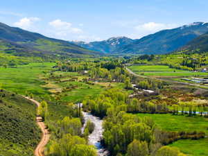Expansive valley setting featuring a winding river, verdant fields, and mature deciduous trees
