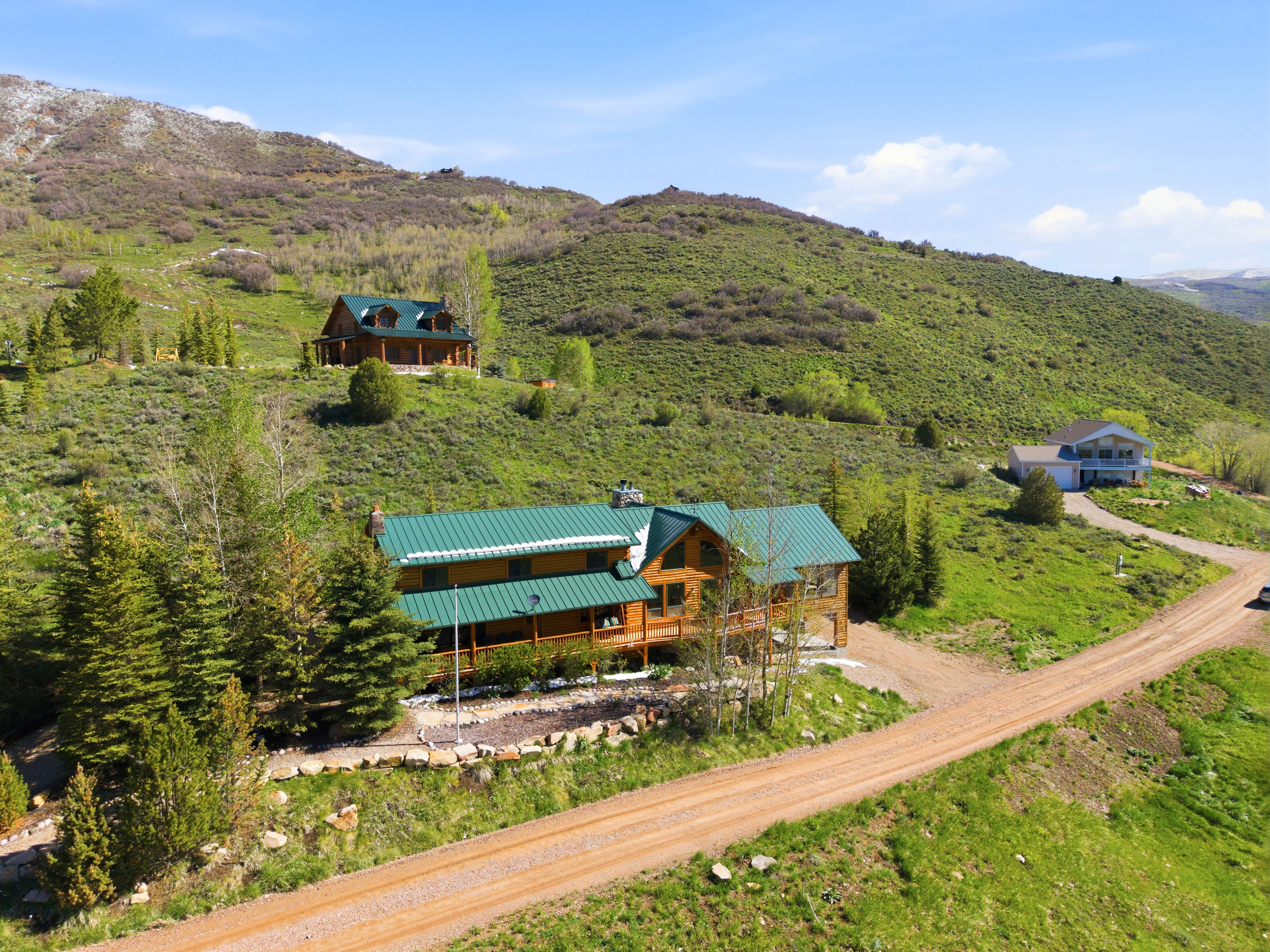 Log-style home with a green metal roof and an expansive wood deck