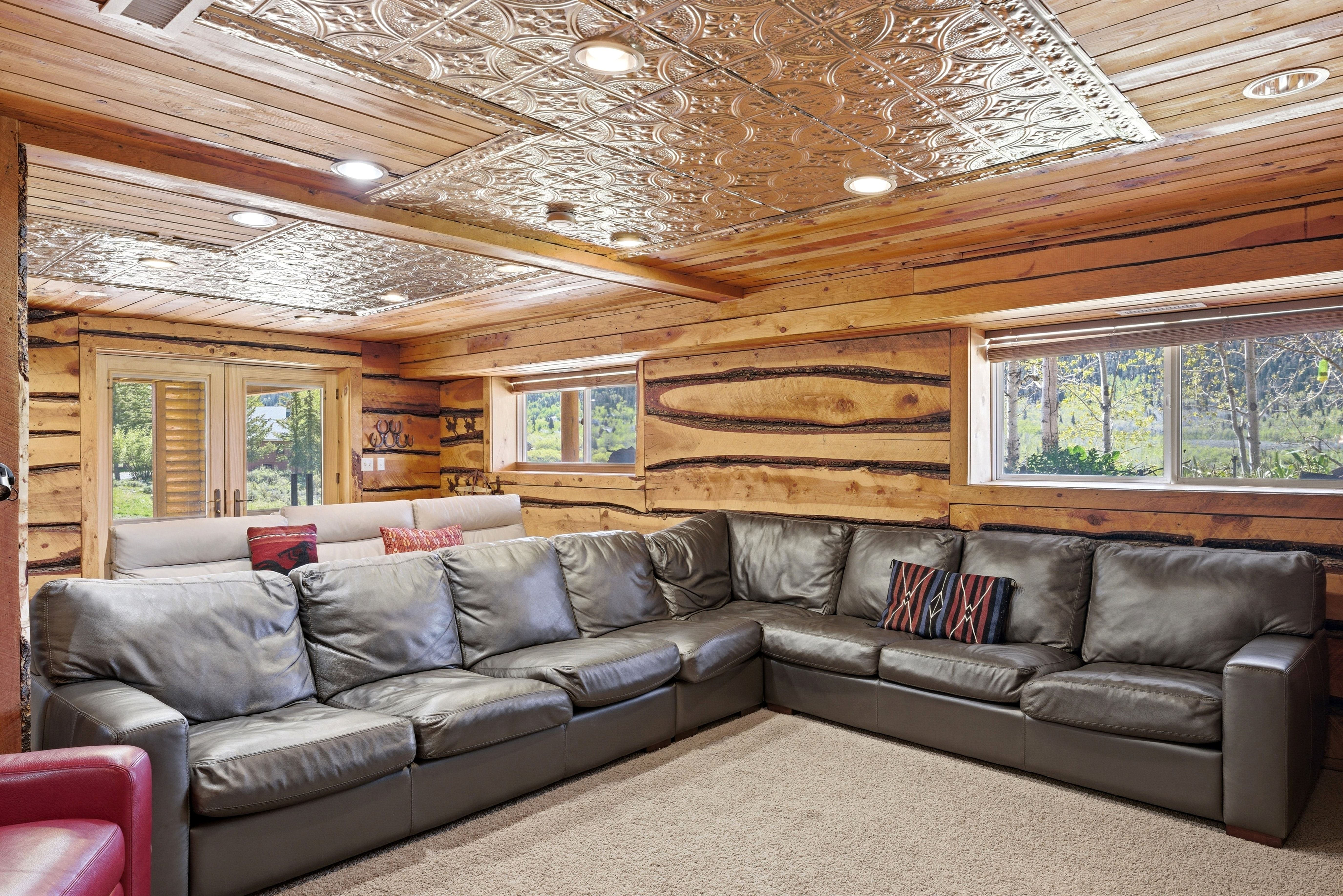 Room featuring log walls, recessed lighting, and a patterned tin ceiling
