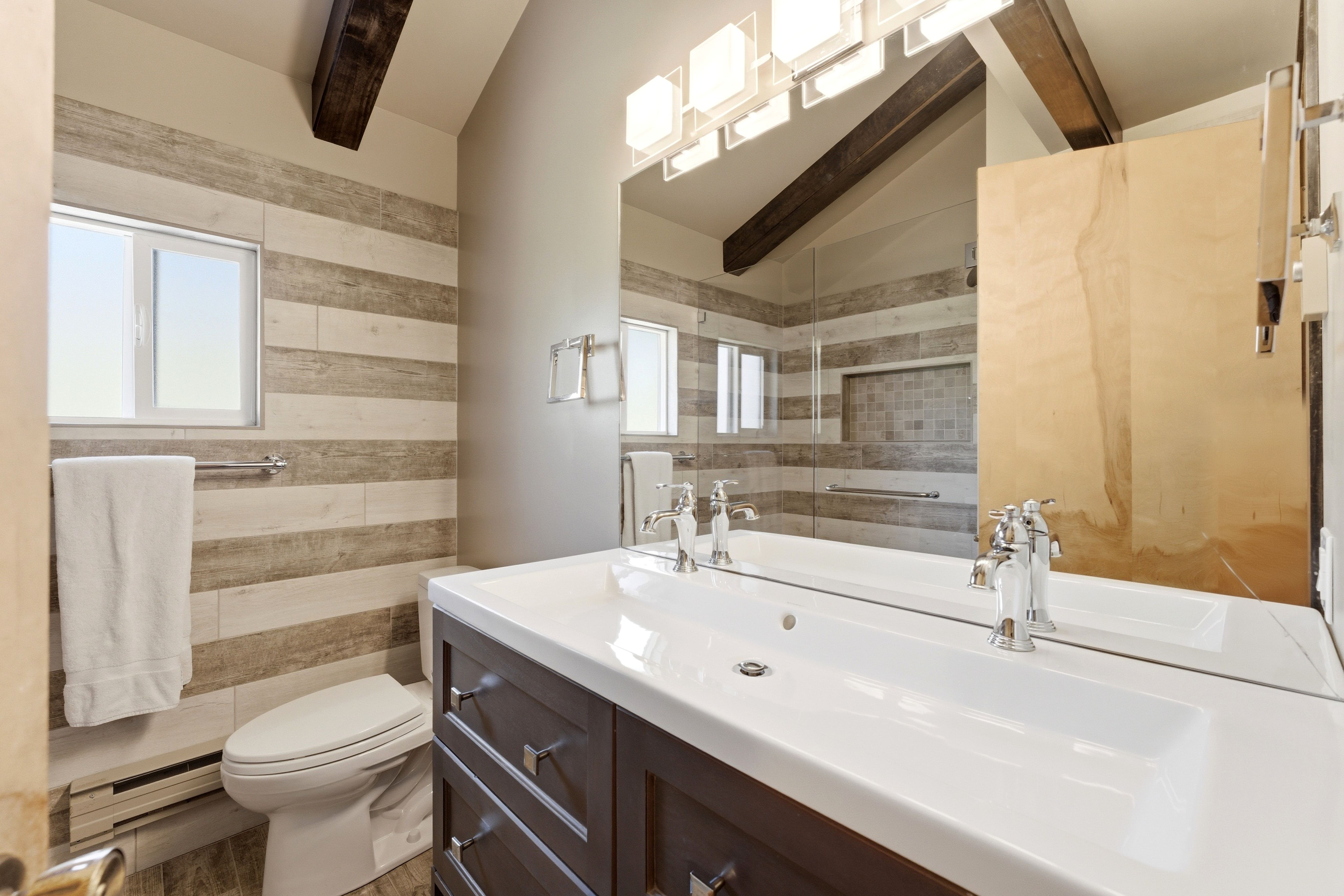 Bathroom featuring a dual-sink vanity with white countertop, chrome fixtures, and dark wood cabinetry