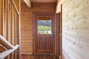 Wood-paneled interior featuring a solid wood door with an upper window, log-style banister, and wood-finish flooring