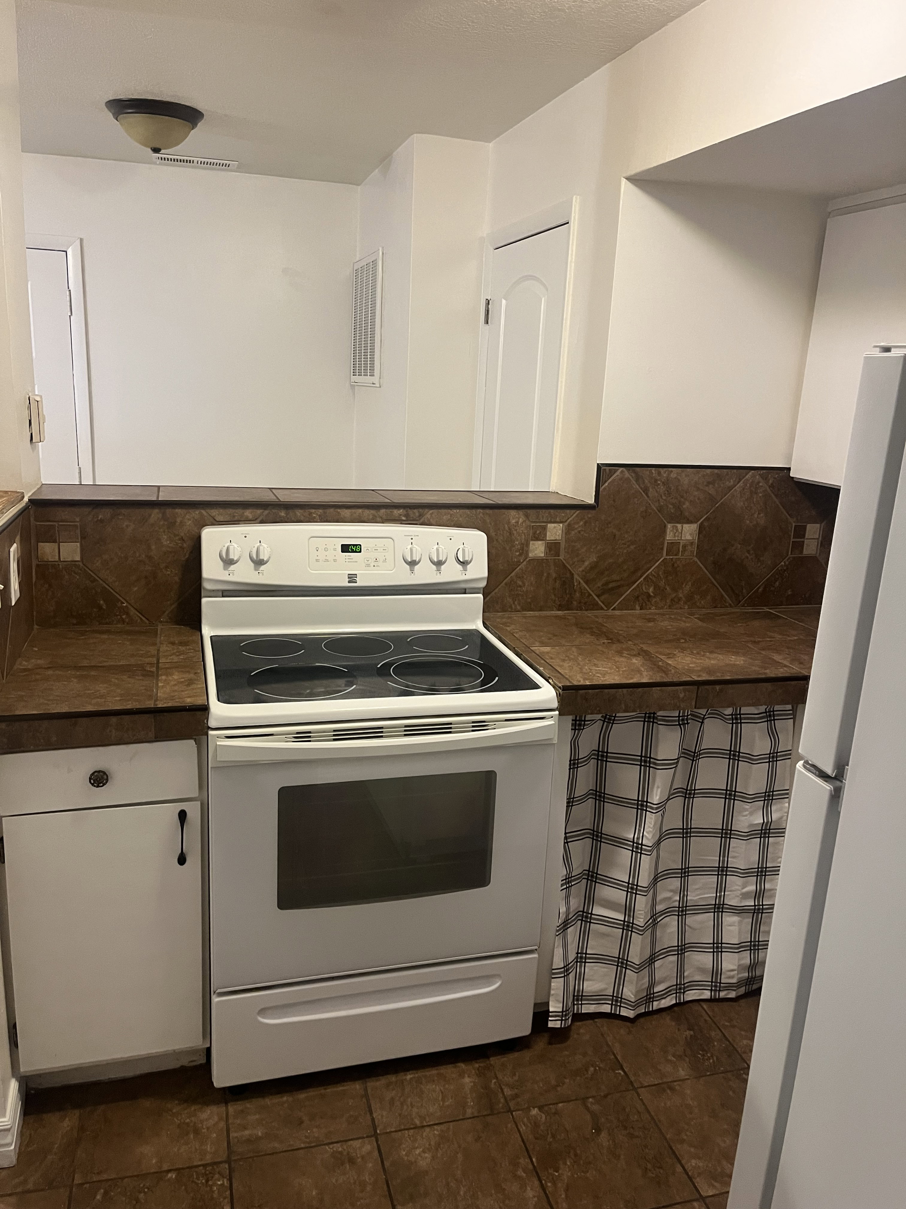 Kitchen featuring a white electric range, dark tile flooring, and a coordinating dark tile backsplash