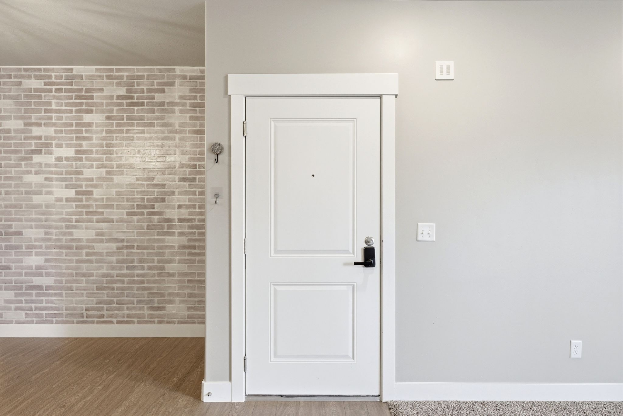 Entryway featuring a white paneled door with black hardware, complementing the light gray wall