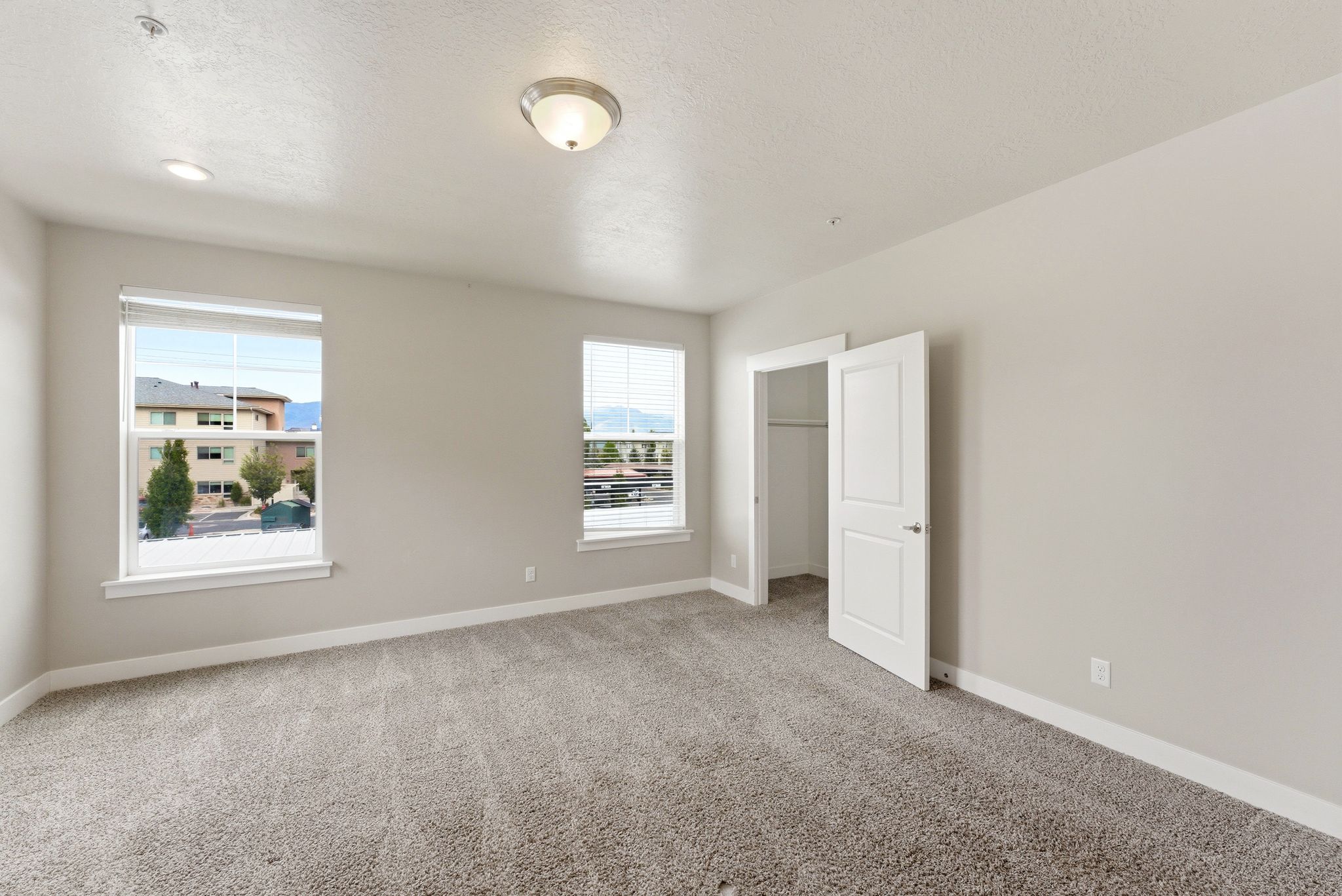 Spacious primary bedroom featuring neutral carpeting and light-toned walls