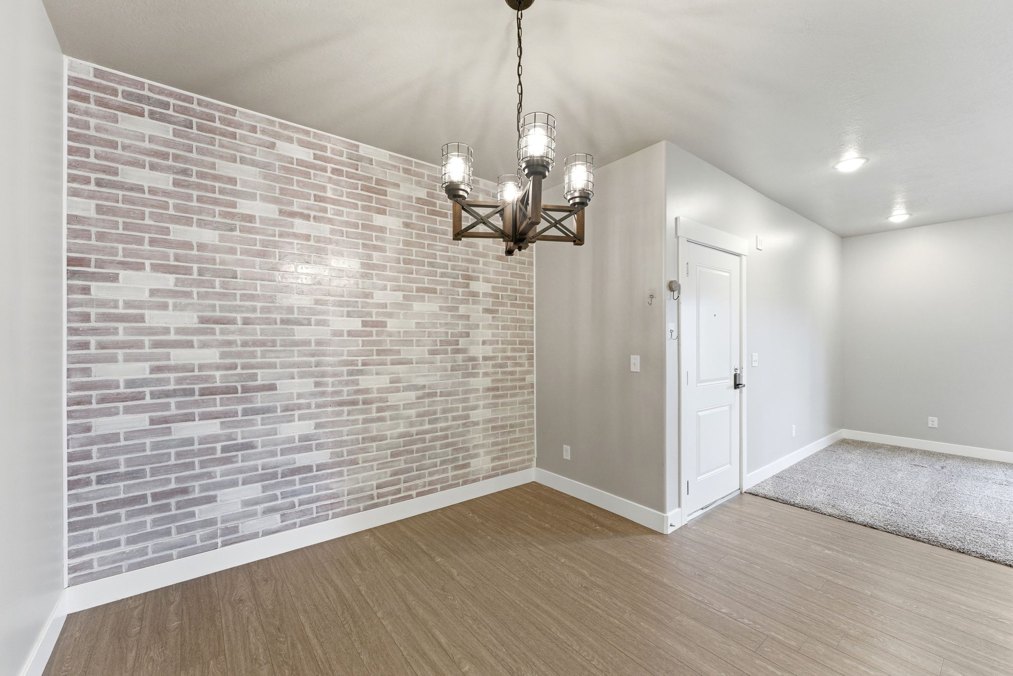 Accent brick wall with wood-finish flooring and a rustic chandelier