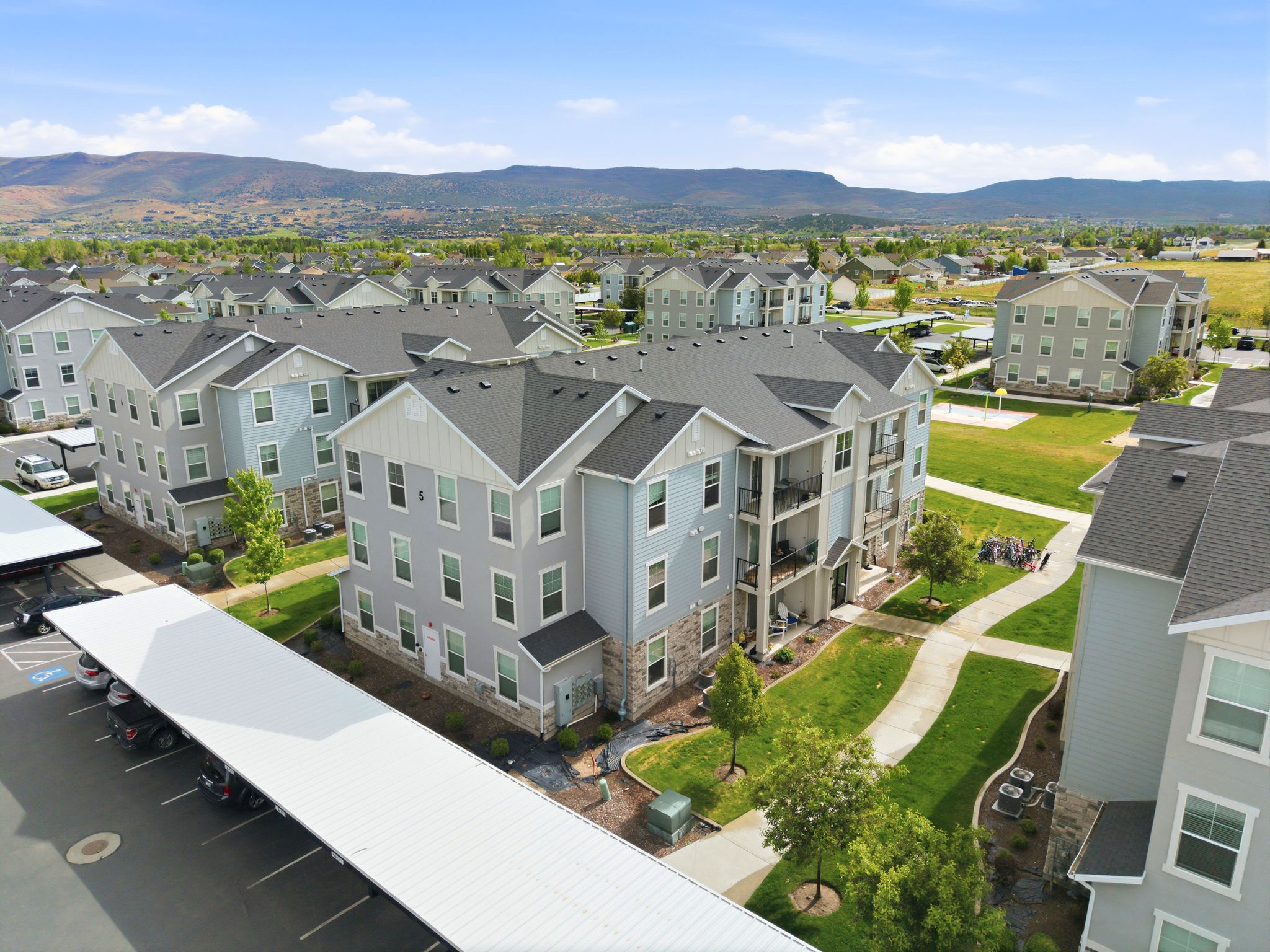 Multi-story apartment building featuring light blue siding, stone veneer accents, and multiple balconies