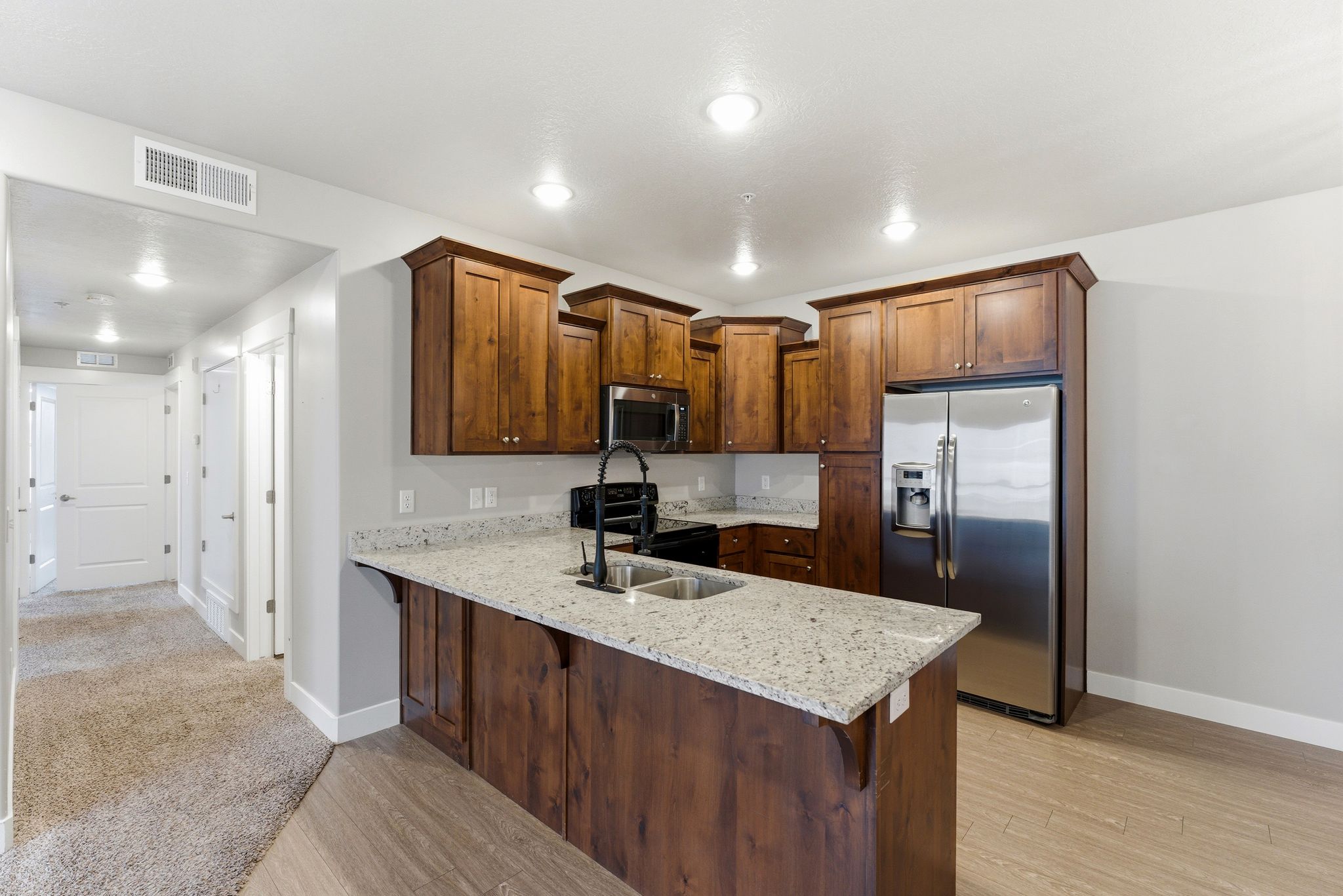 Modern kitchen featuring rich wood cabinetry, granite countertops, and stainless steel appliances
