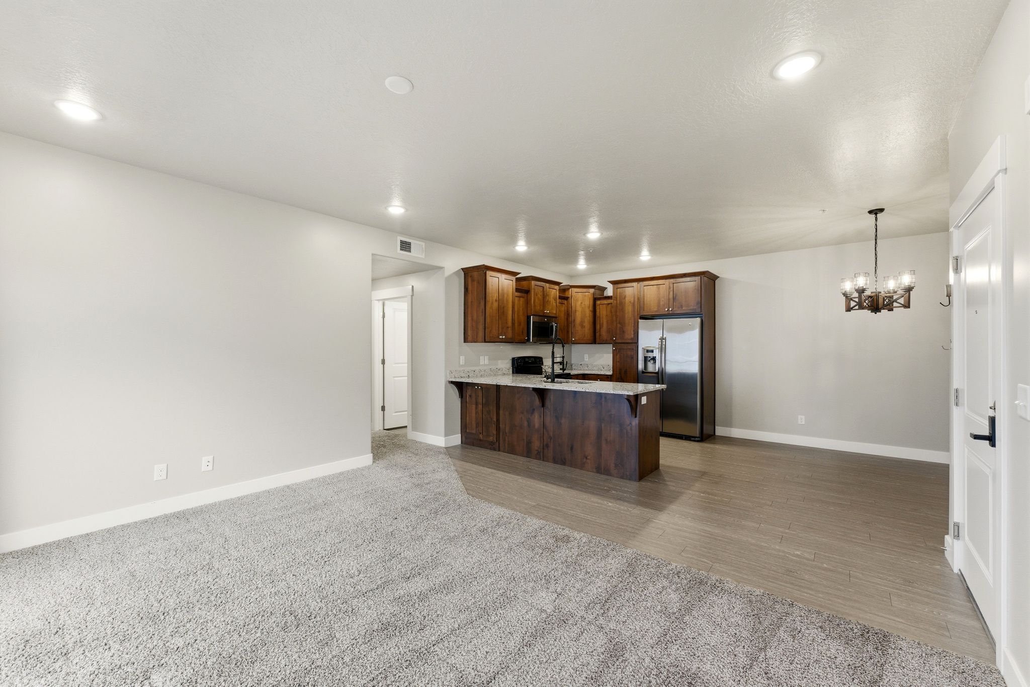 Open-concept living area featuring a kitchen with wood cabinetry, stainless steel appliances, and a breakfast bar