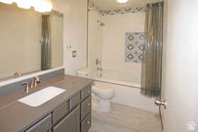 Bathroom featuring a gray vanity with an integrated sink, brushed nickel faucet, and a large wall mirror