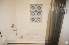 Bathroom featuring a jetted tub, white tile surround, brushed nickel fixtures, and decorative accent tiles