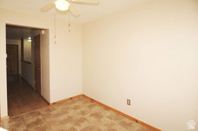 Room featuring a ceiling fan with light fixture, neutral wall color, and patterned floor tiles
