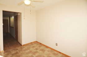Room featuring a ceiling fan with light fixture, neutral wall color, and patterned floor tiles