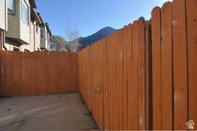 Private outdoor space featuring a wood fence, concrete ground cover, and mountain scenery