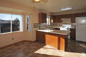 Kitchen with wood-finish cabinetry, light countertops, and a tiled backsplash